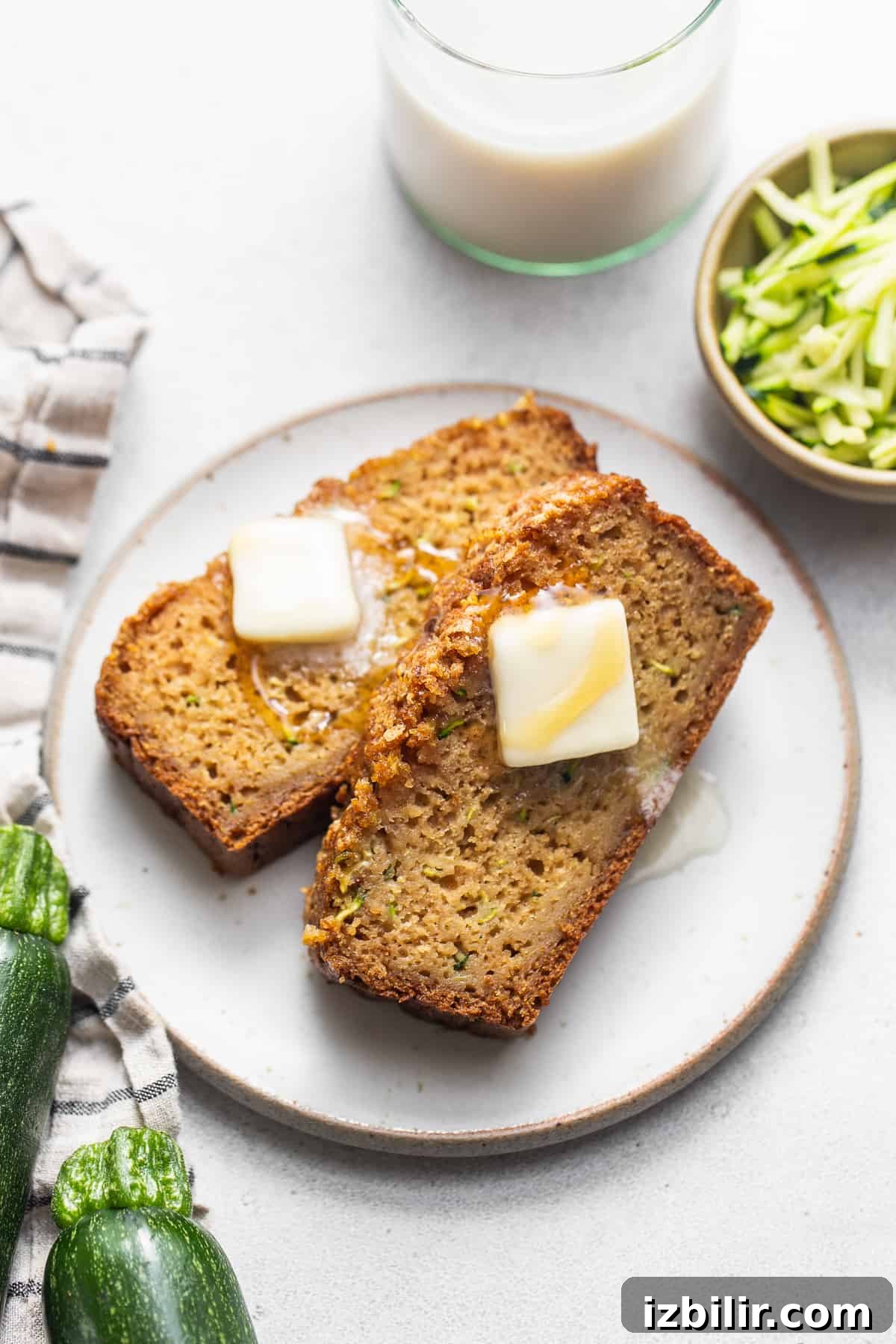 Moist Zucchini Bread with Cinnamon and Walnuts 7 A white plate topped with two slices of bread.