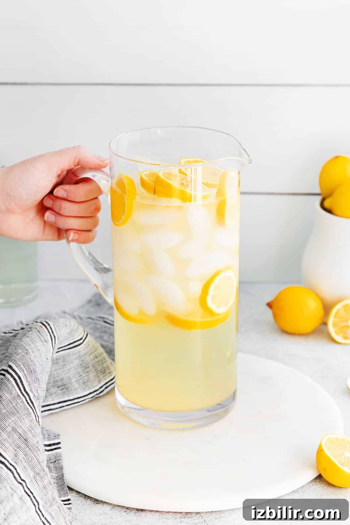 Zesty Homemade Lemonade Recipe for Summer 2 A pitcher of lemonade with ice and slices of lemons.