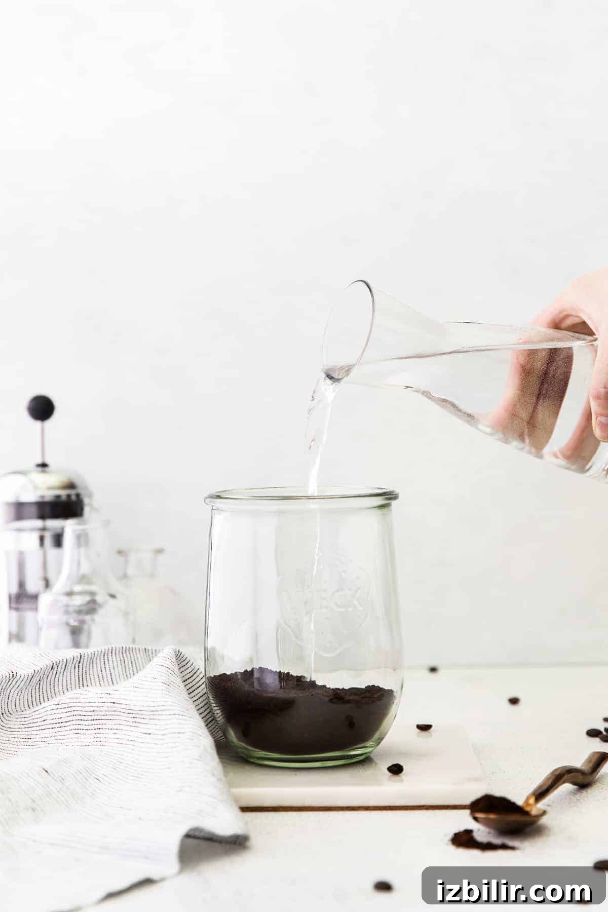 Cold Brew Coffee Recipe: Brew Smooth Coffee at Home 6 Pouring water over coffee grounds to make cold brew coffee.