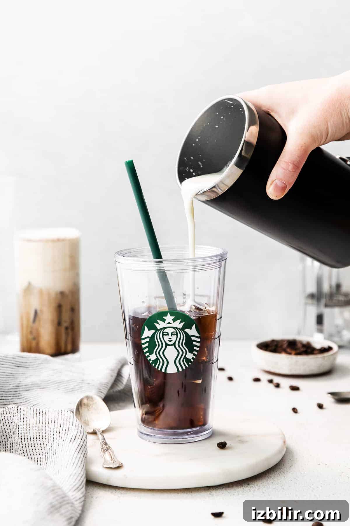 Pouring sweet cream into a glass of cold brew.