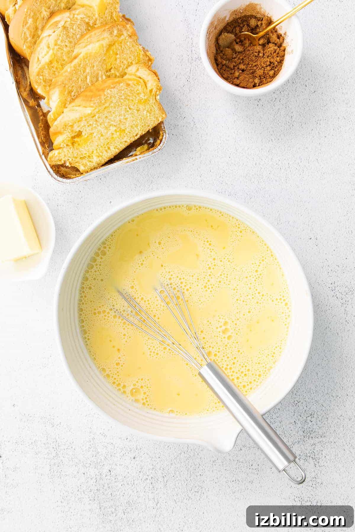 egg wash for french toast in a bowl with slices of bread next to it