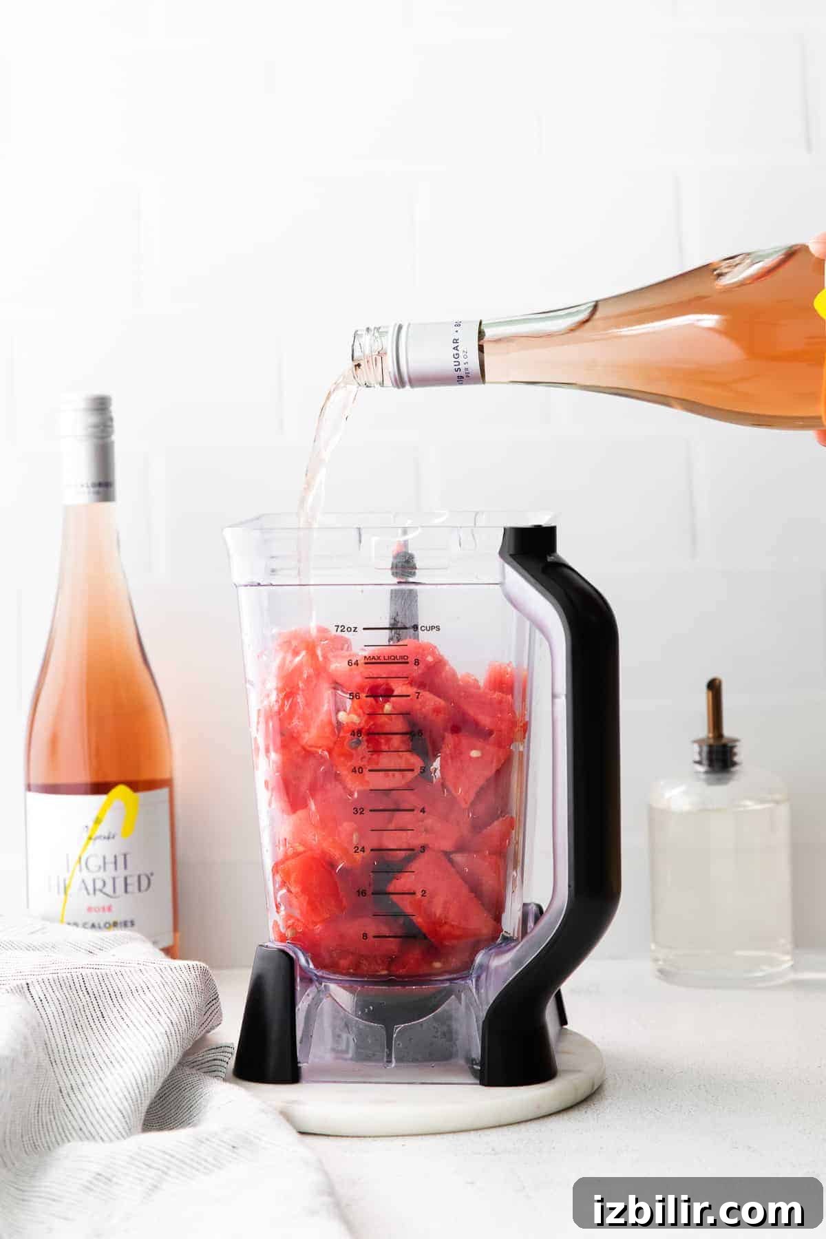 3 Wine Slushie Recipes for Summer Sipping 3 pouring a bottle of rosé into a blender with frozen watermelon