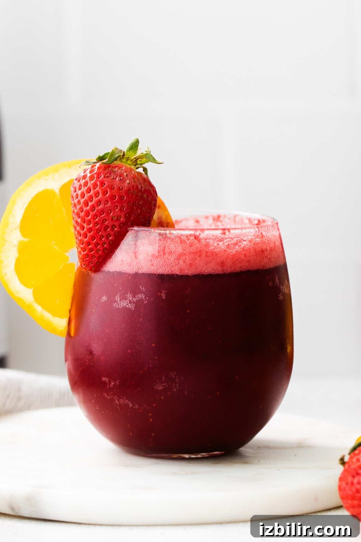3 Wine Slushie Recipes for Summer Sipping 6 a red drink with a slice of lemon on top of it.
