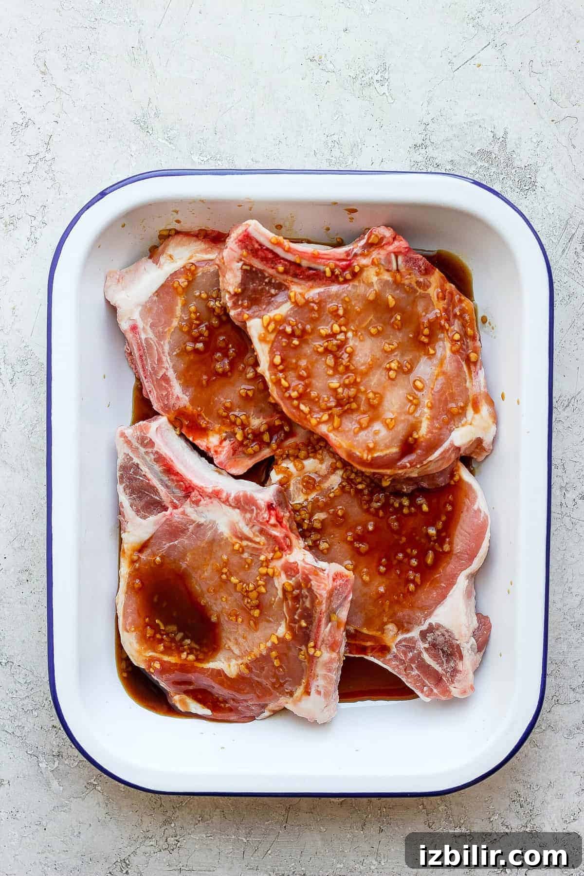 This grilled pork chops recipe comes out so juicy and tender on the inside and has gorgeous, charred grill marks on the outside. pork chops marinating in dish.