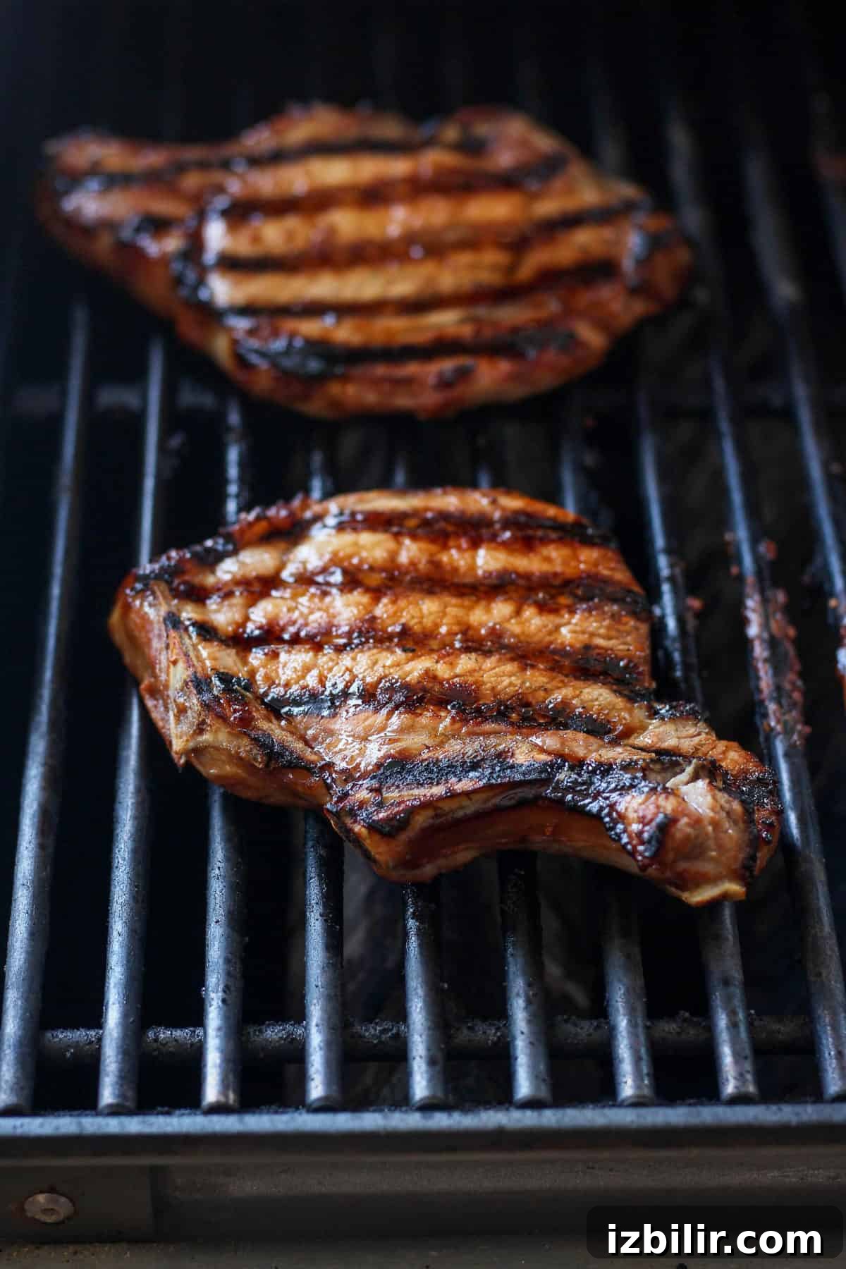 These grilled pork chops are sweet and savory and so juicy! Learn how to grill pork chops perfectly every time with this delicious recipe. pork chops grilling on grill.