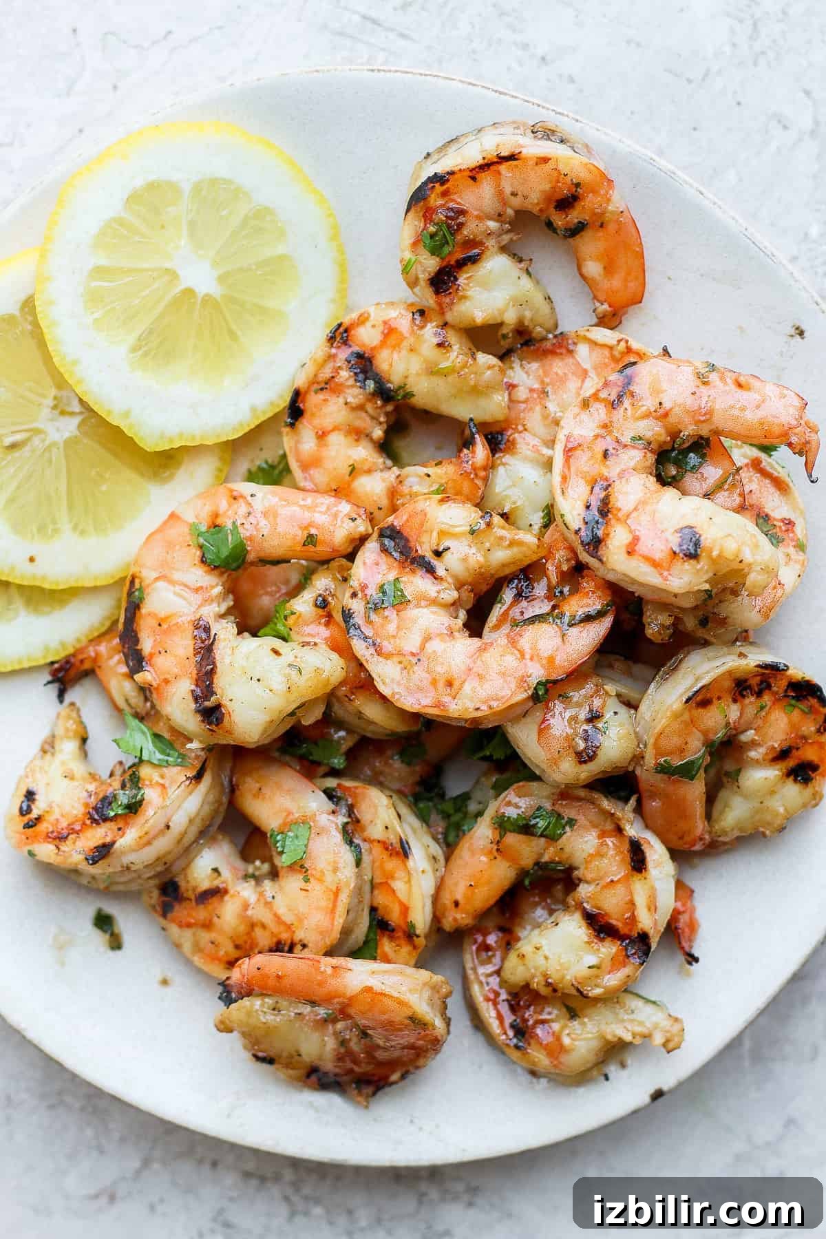 Get perfectly grilled shrimp every single time with this easy and fool-proof step-by-step tutorial on how to grill shrimp! Grilled shrimp on a plate with lemon slices.