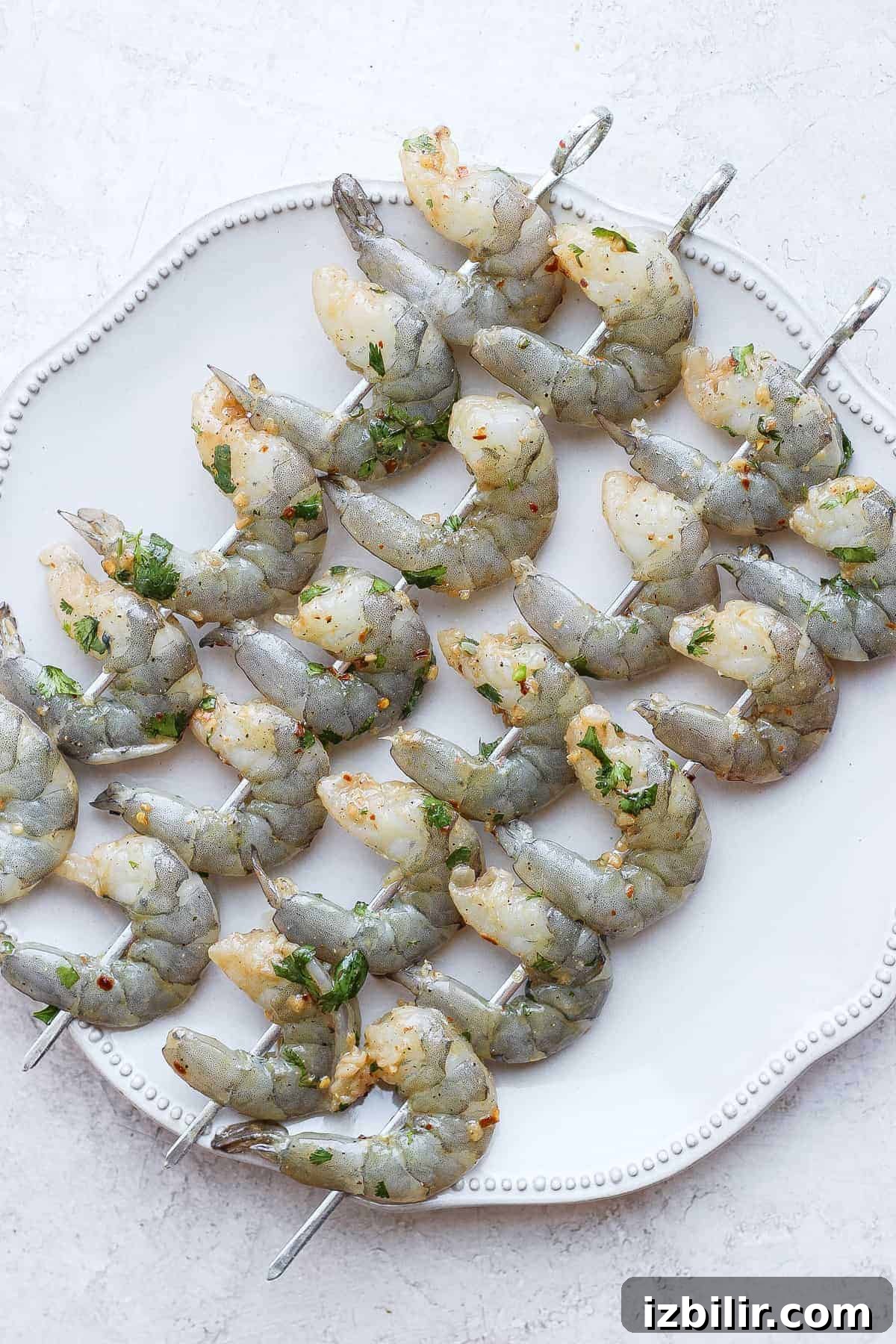 Raw marinated shrimp on skewers Raw marinated shrimp on skewers on a plate.