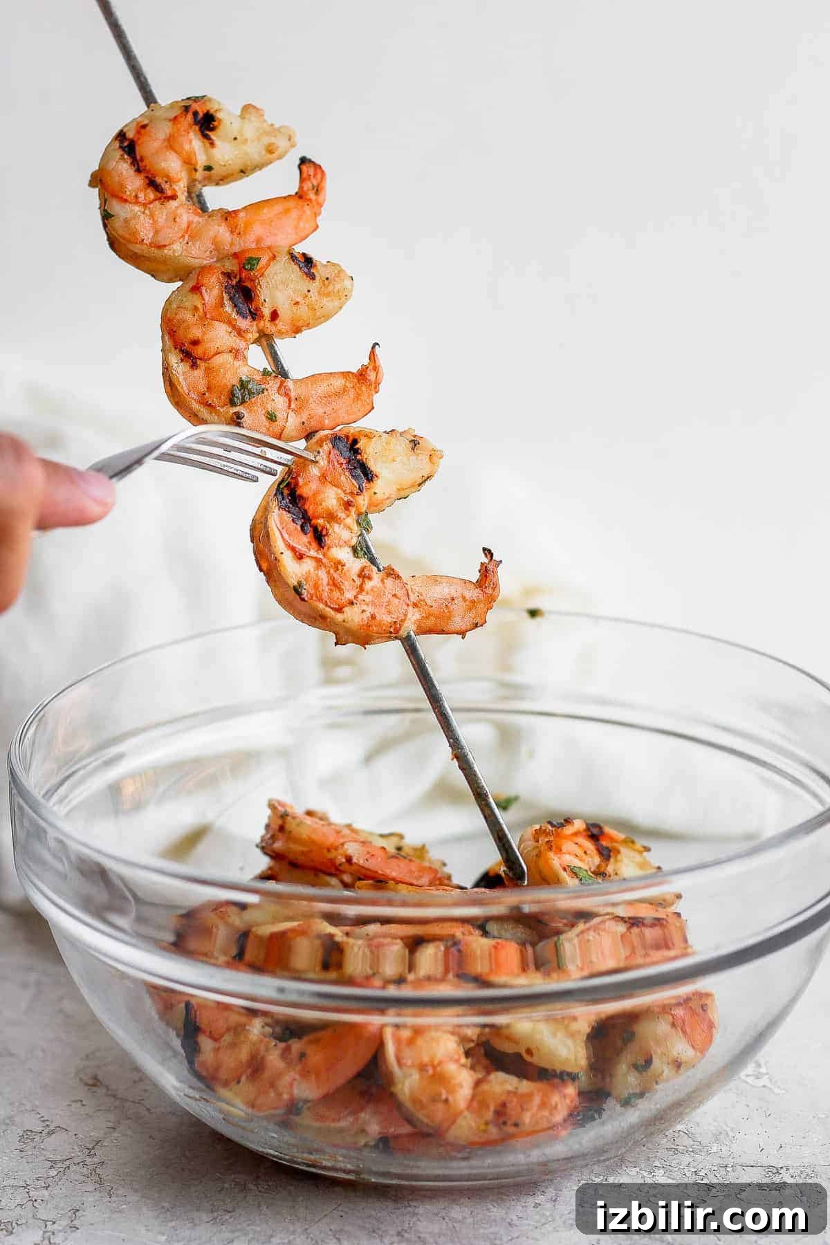 Serve grilled shrimp after removing from skewers Taking grilled shrimp off skewers and putting them into a bowl.
