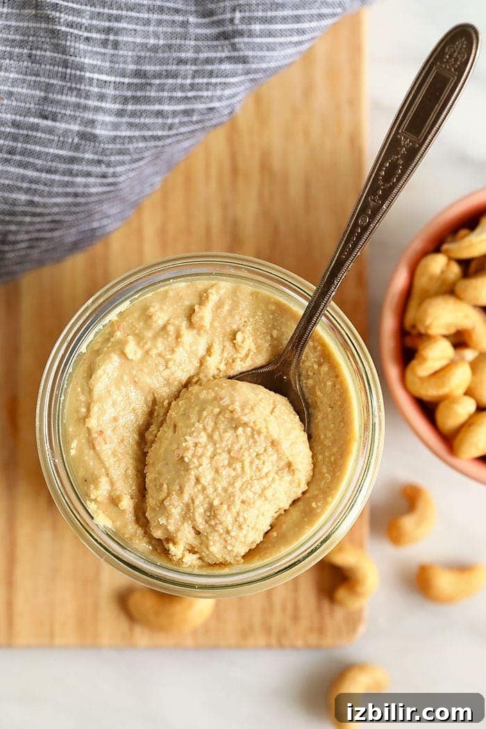 Creamy cashew butter in a jar cashews butter in a glass jar with a spoon