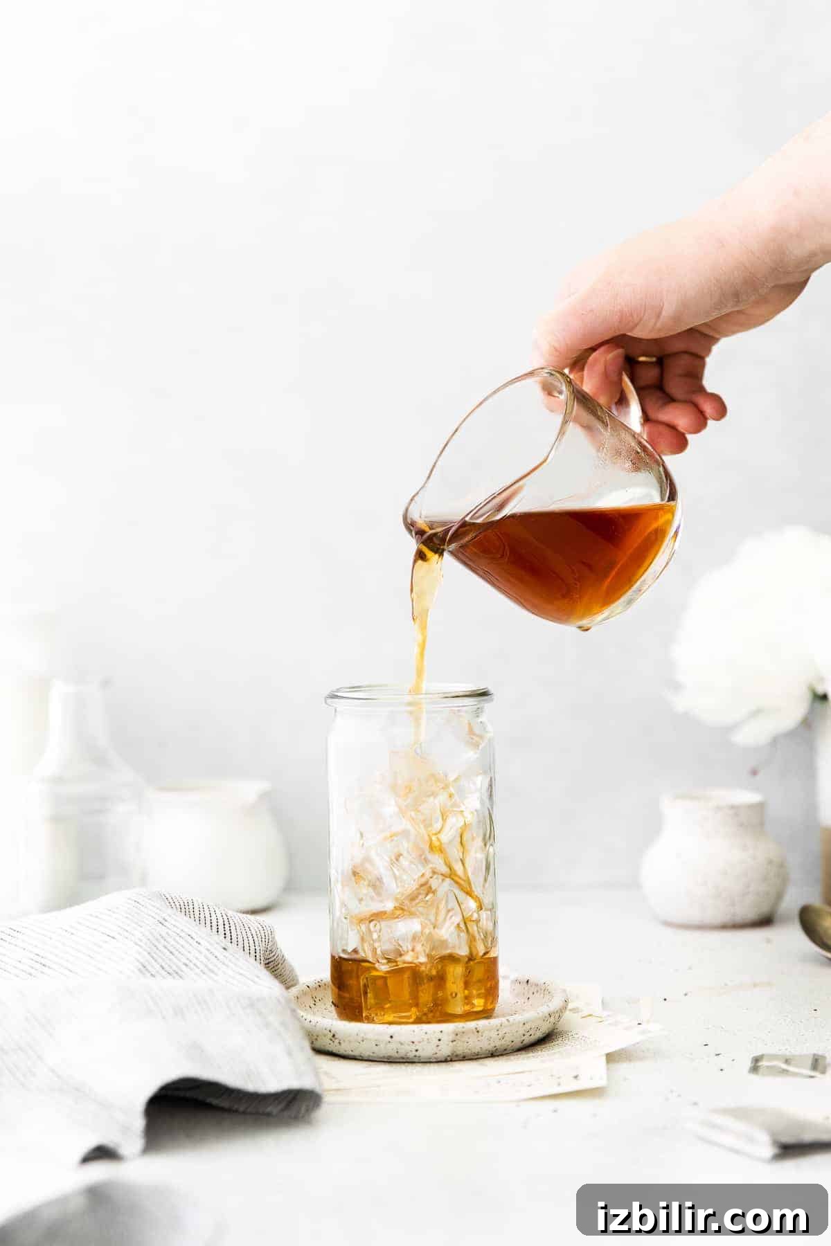 pouring tea into a glass with ice