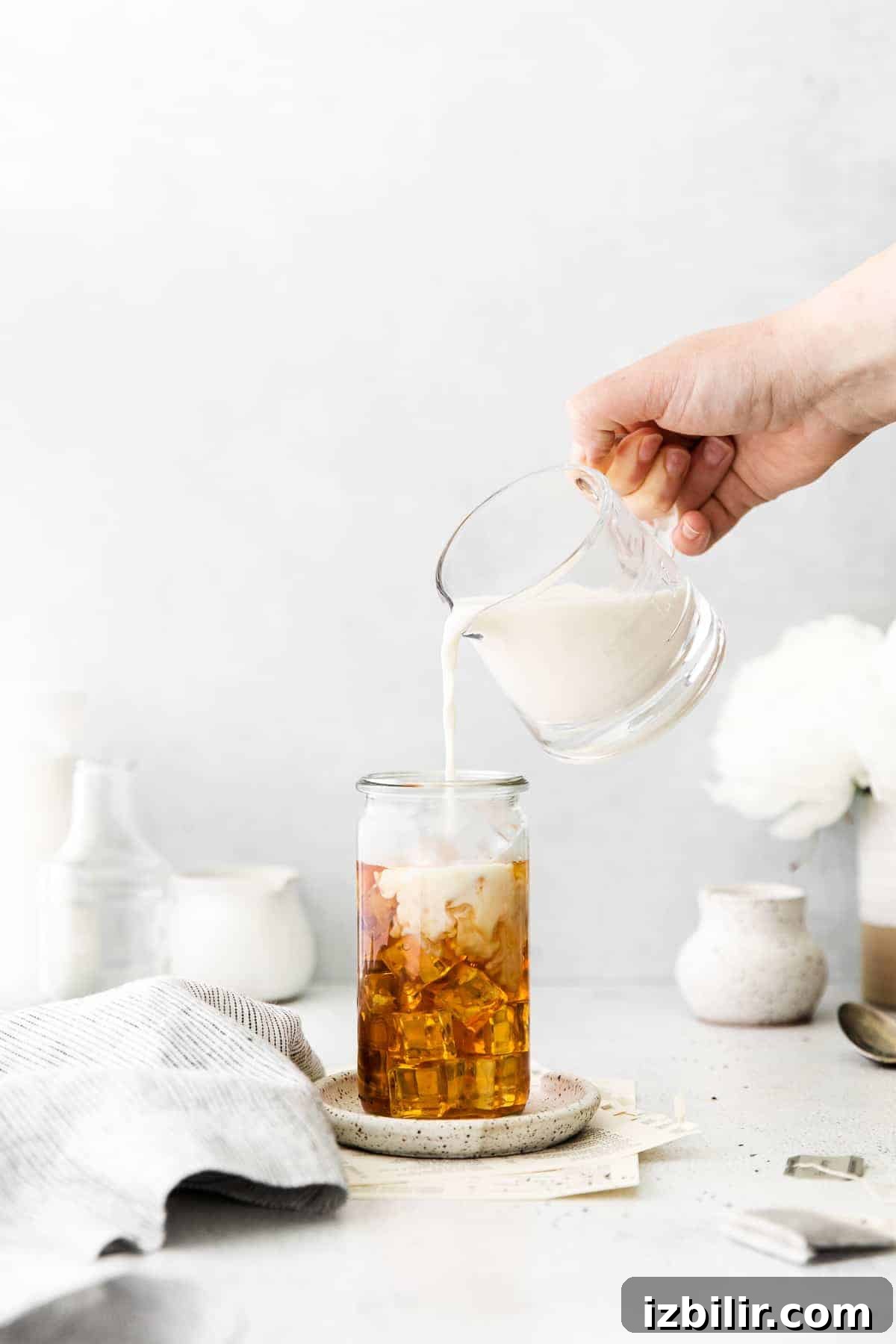 pouring milk on top of iced tea