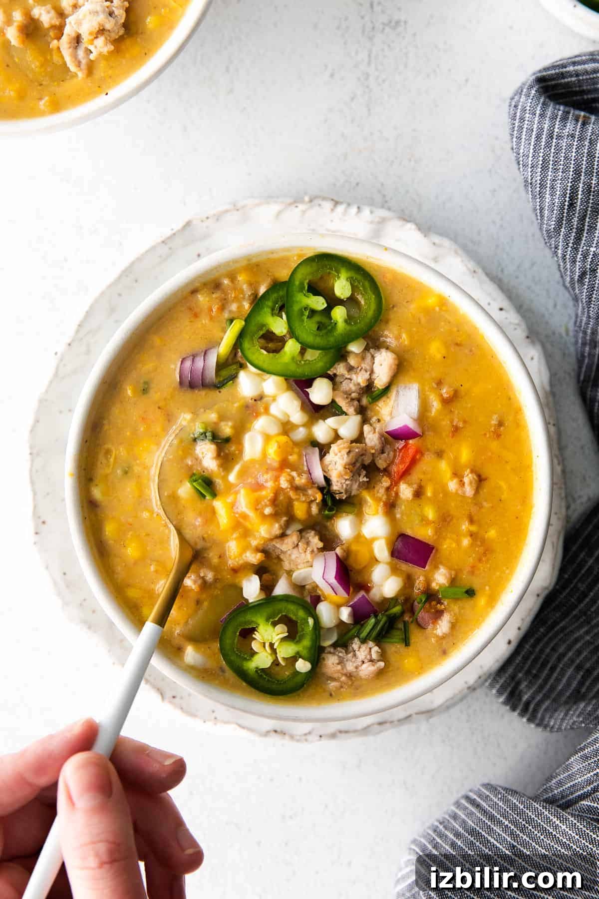 Sweet corn season is here and we're sharing a delicious corn chowder recipe made with fresh corn cobs, potatoes, a little ground pork, and yummy spices. corn chowder in bowl
