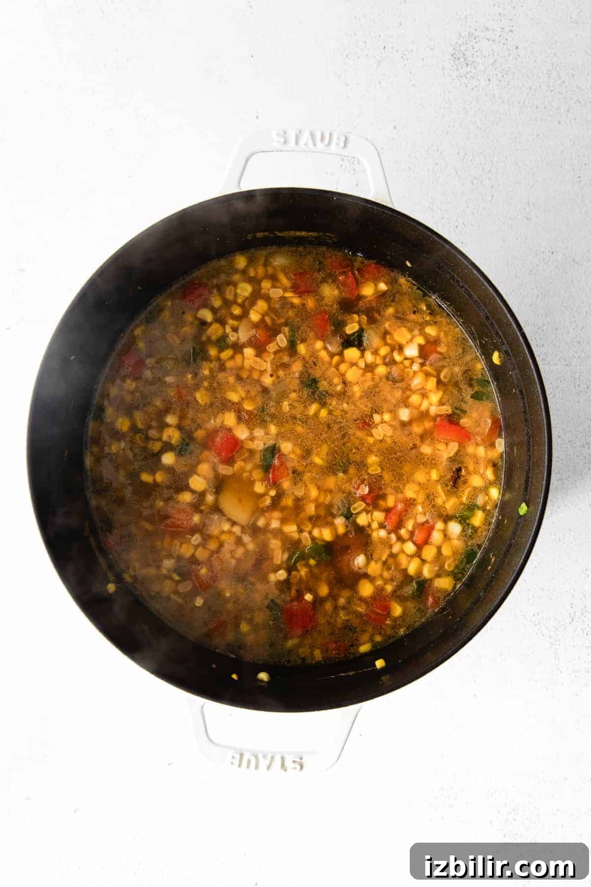 A pot of corn chowder simmering on the stove. soup in Dutch oven