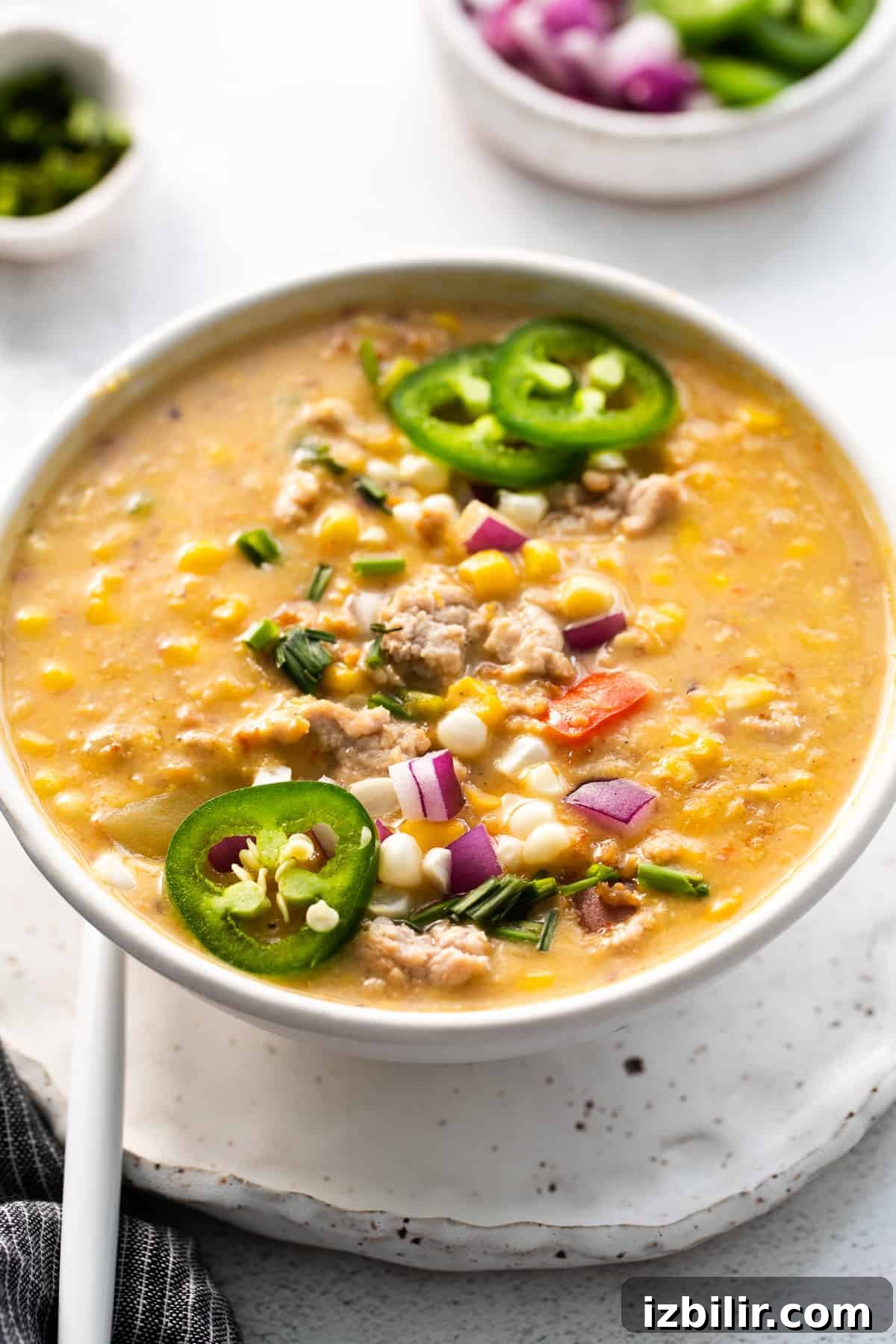 A bowl of corn chowder finished with fresh herbs and toppings. corn chowder with toppings