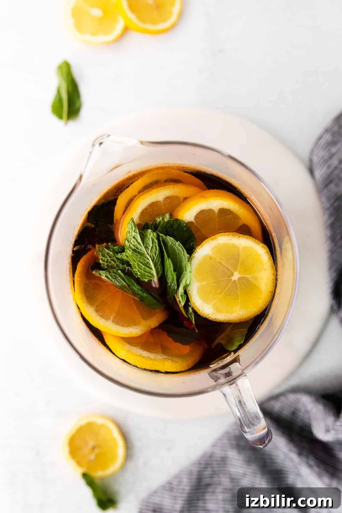 Pitcher of iced tea garnished with fresh lemons and mint