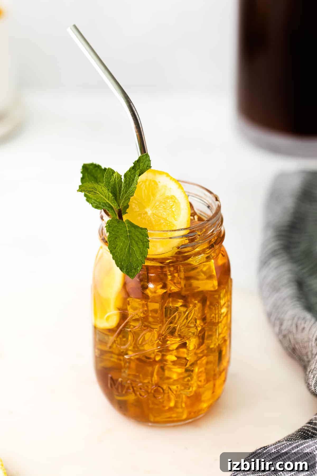 Mason jar of iced tea garnished with a slice of fresh lemon and a sprig of fresh mint