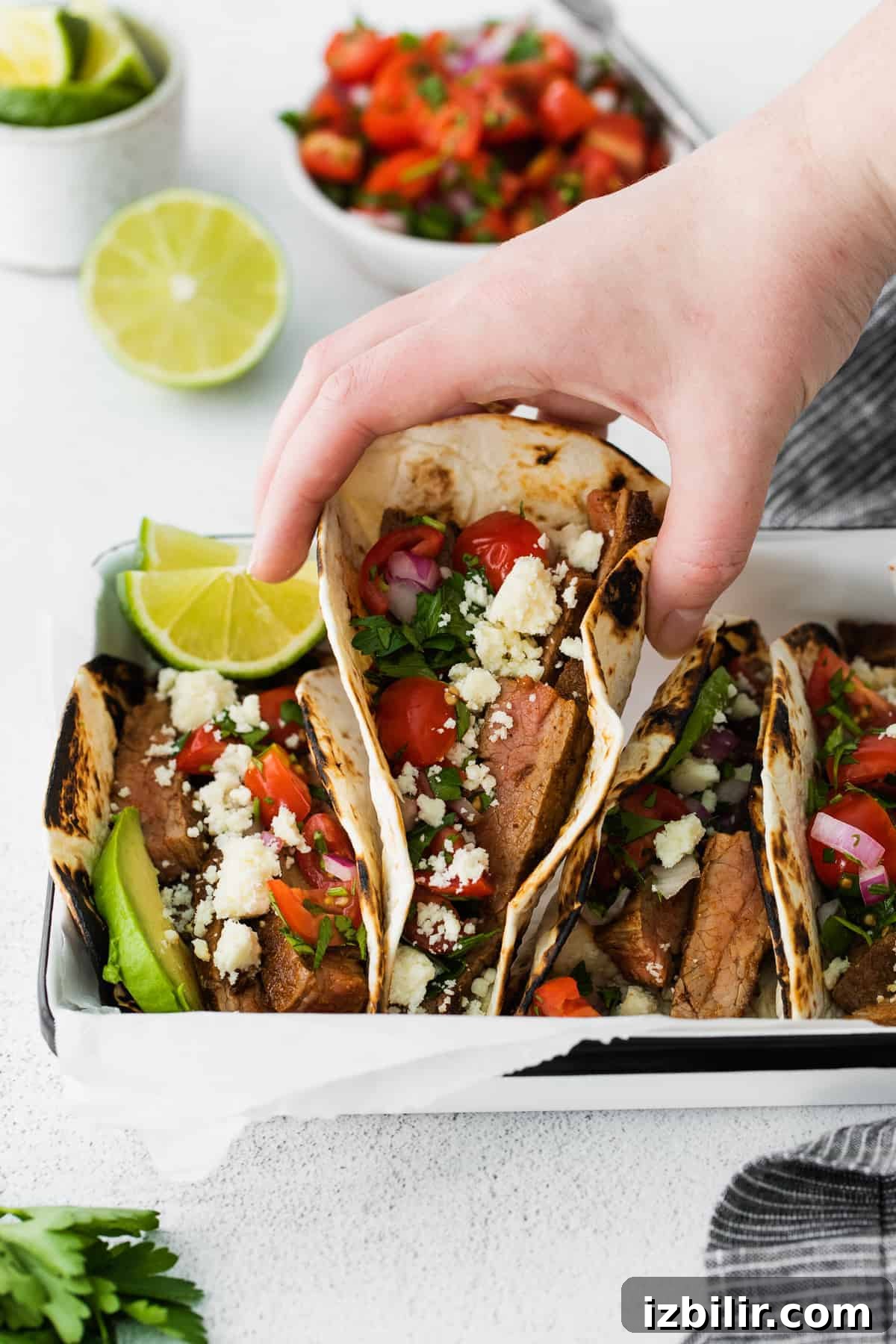 Hand grabbing a steak taco hand grabbing a steak taco from a platter of steak tacos