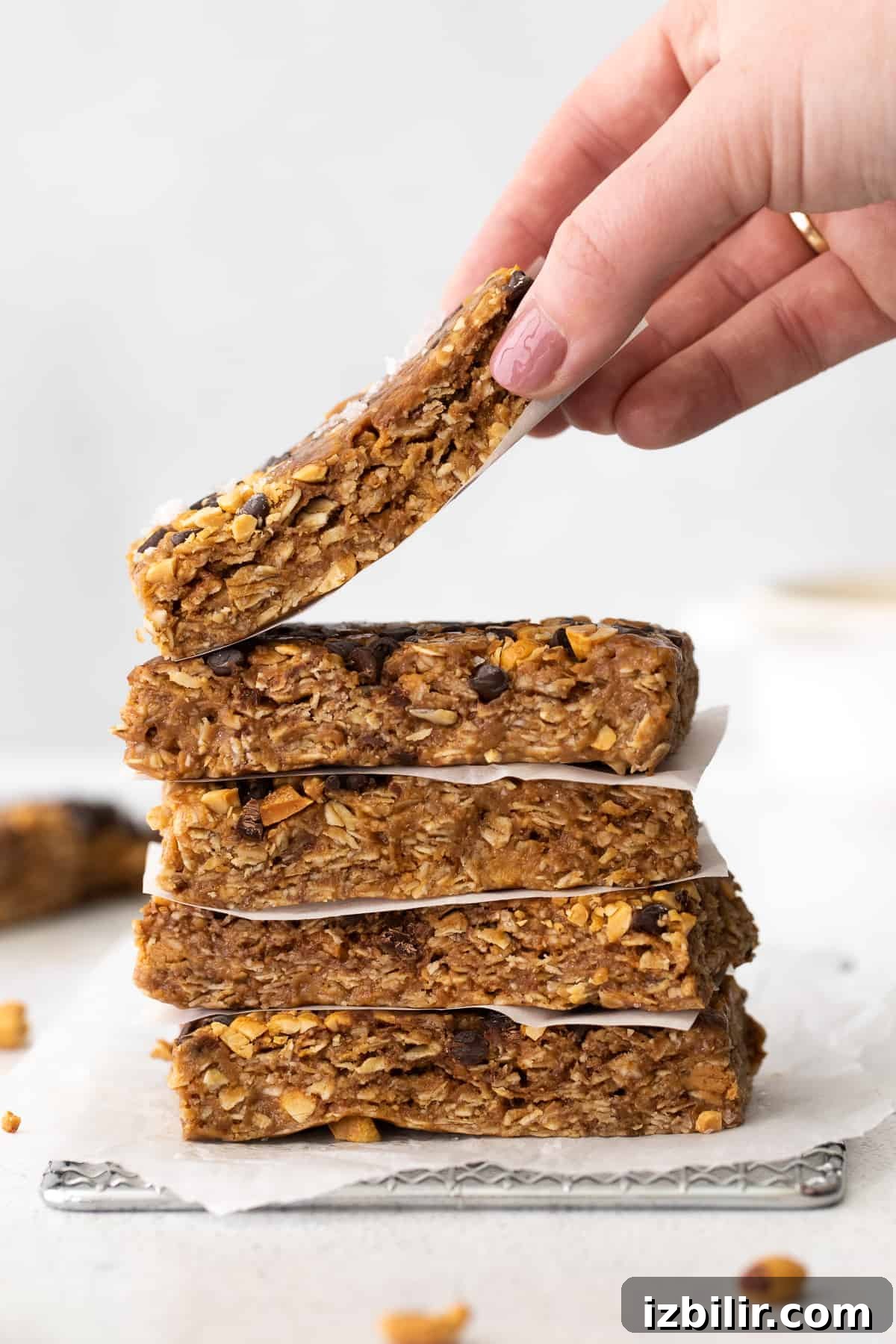 Homemade granola bars with peanut butter and chocolate chips hand holding granola bar