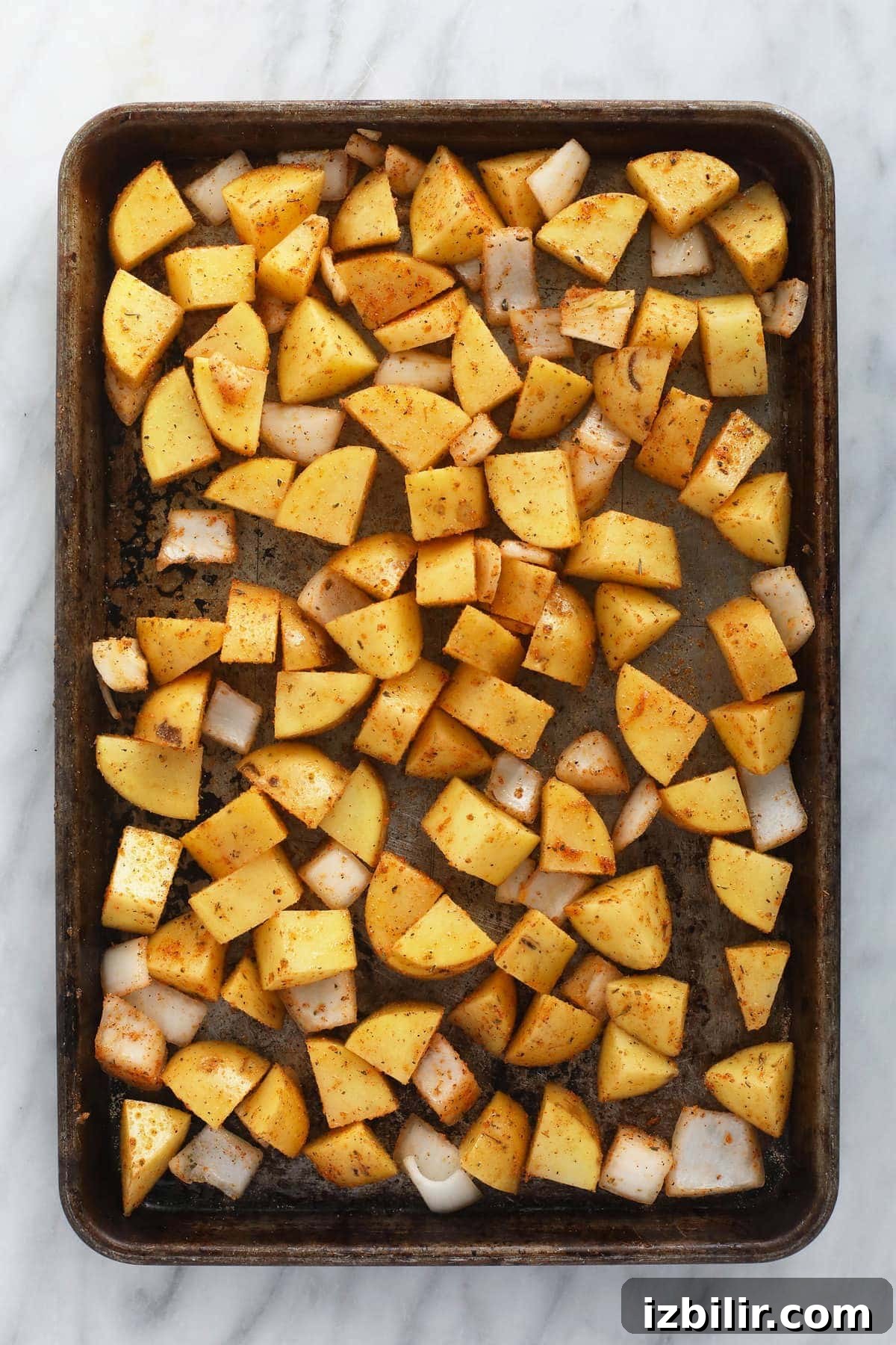 sliced breakfast potatoes on a baking sheet, ready to be baked