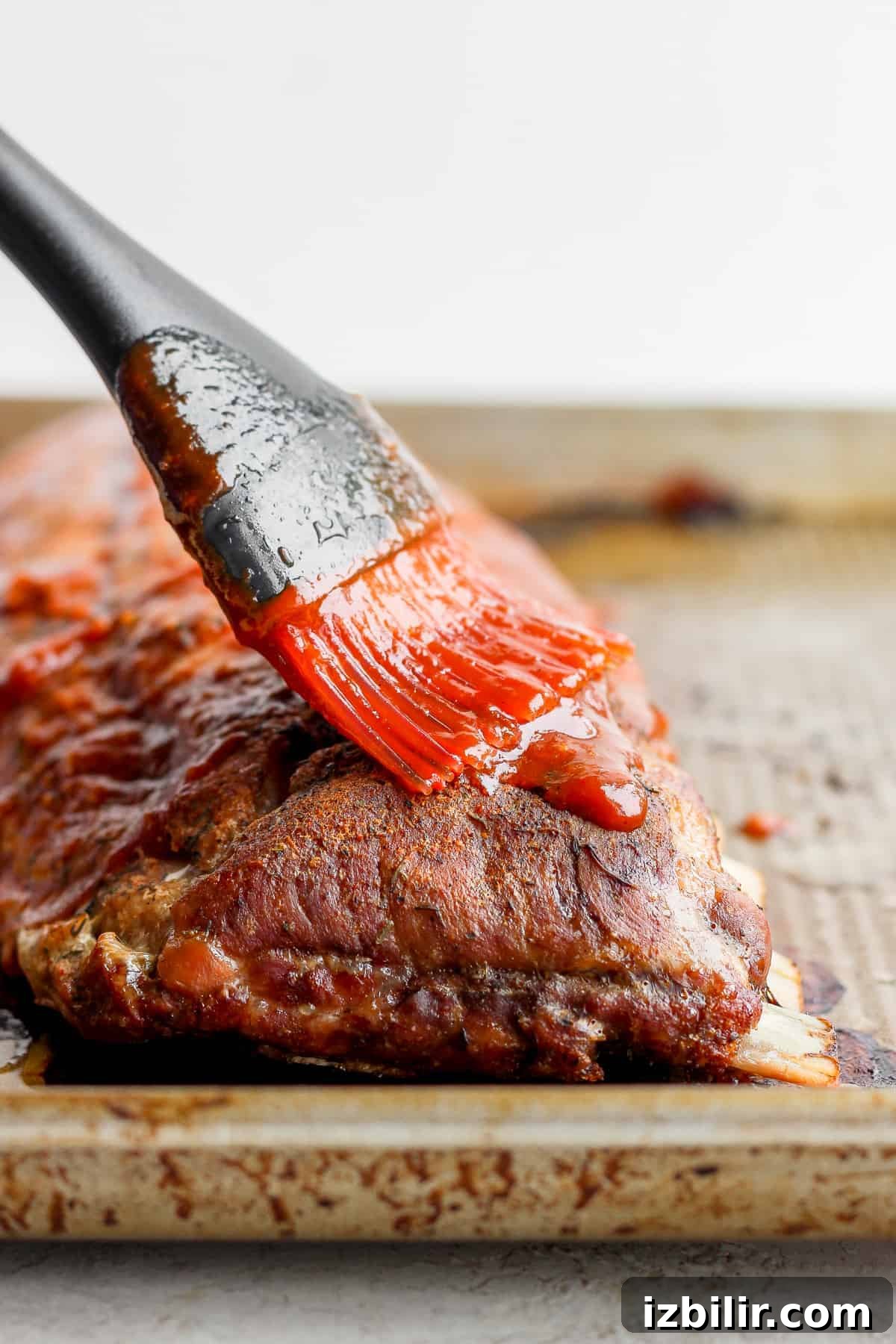 How to Make Fall-Off-the-Bone Oven Ribs 8 Brushing bbq sauce on ribs