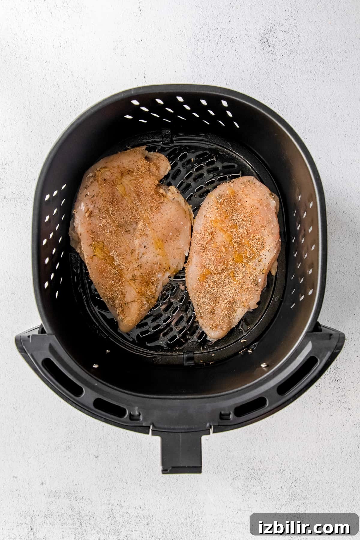 Raw chicken placed in air fryer basket raw chicken in air fryer