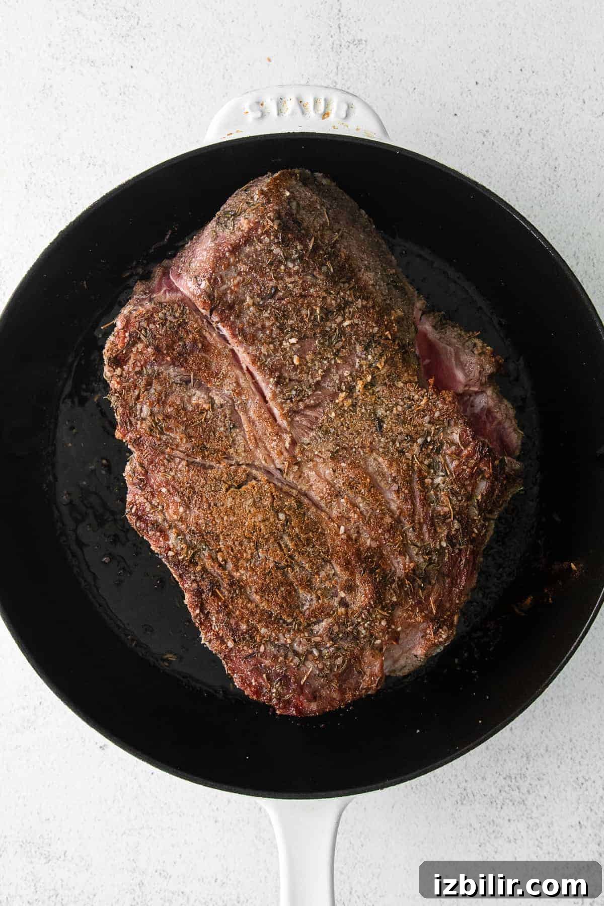 Searing chuck roast before slow cooking chuck roast being seared in a cast iron skillet