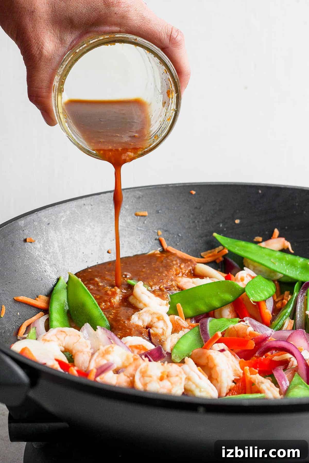 Pour sauce into pan and cook until thickened stir fry sauce being poured over a stir fry in a skillet