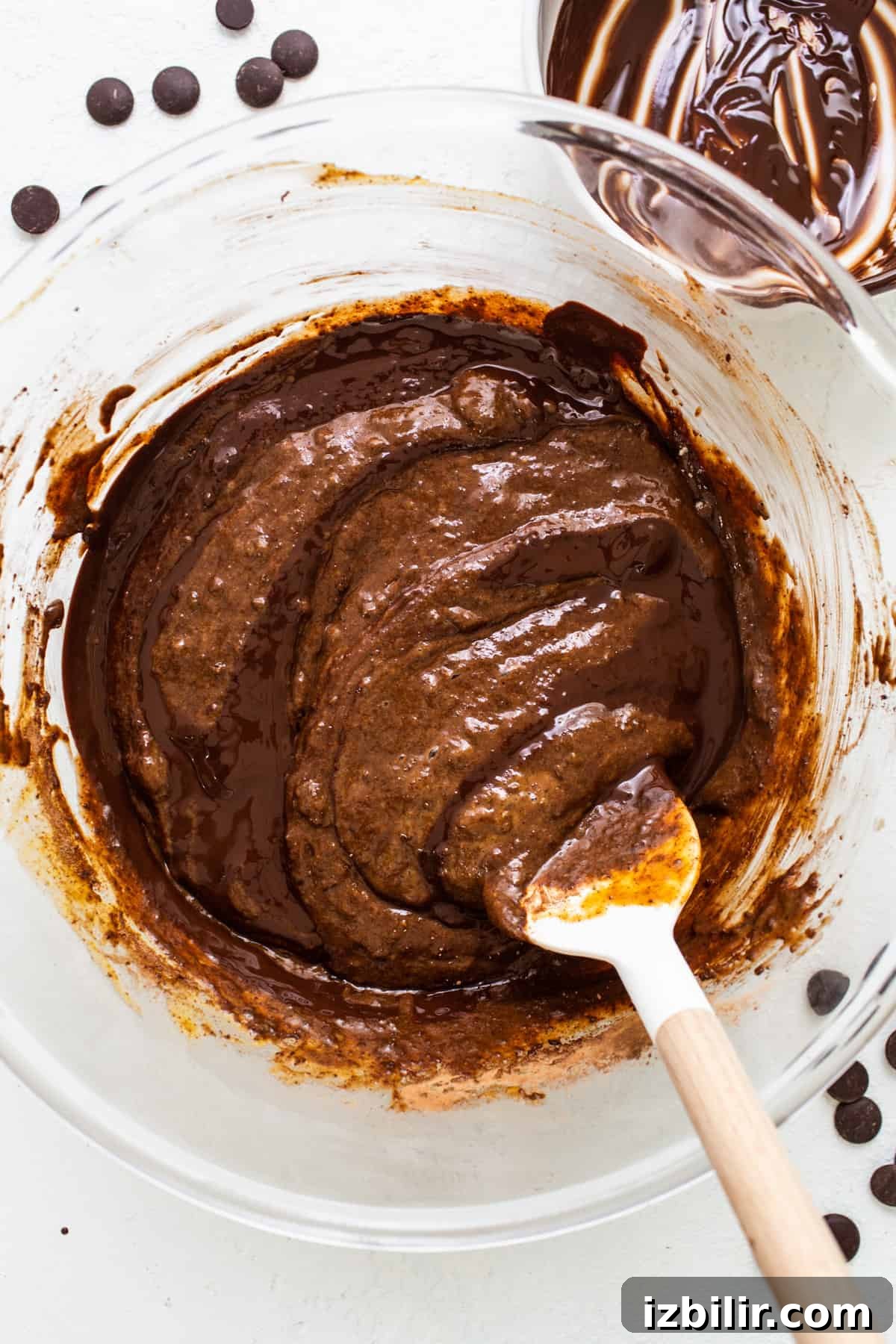 A bowl of chocolate pudding with a wooden spoon.