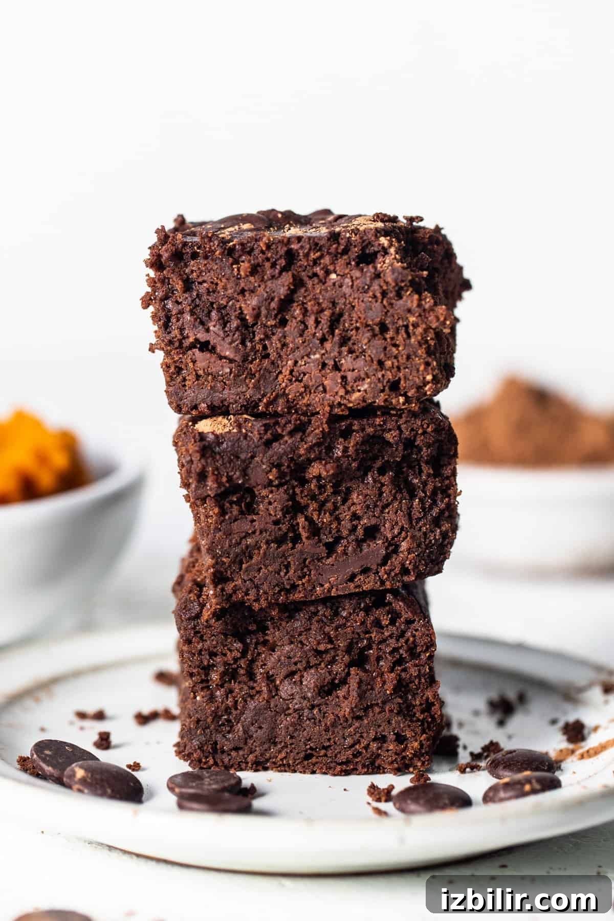 A stack of brownies sitting on top of a white plate.