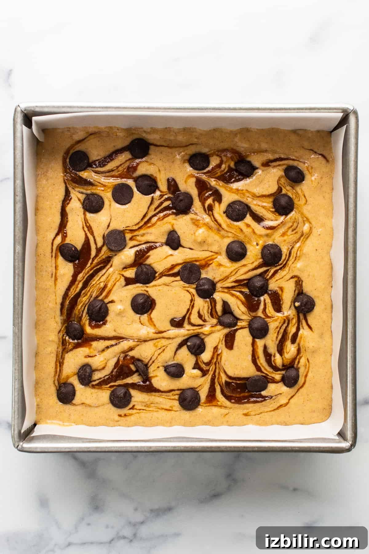 Brown Sugar Swirl Pumpkin Breakfast Cake Recipe 4 A brownie with chocolate chips and caramel sauce in a baking pan.