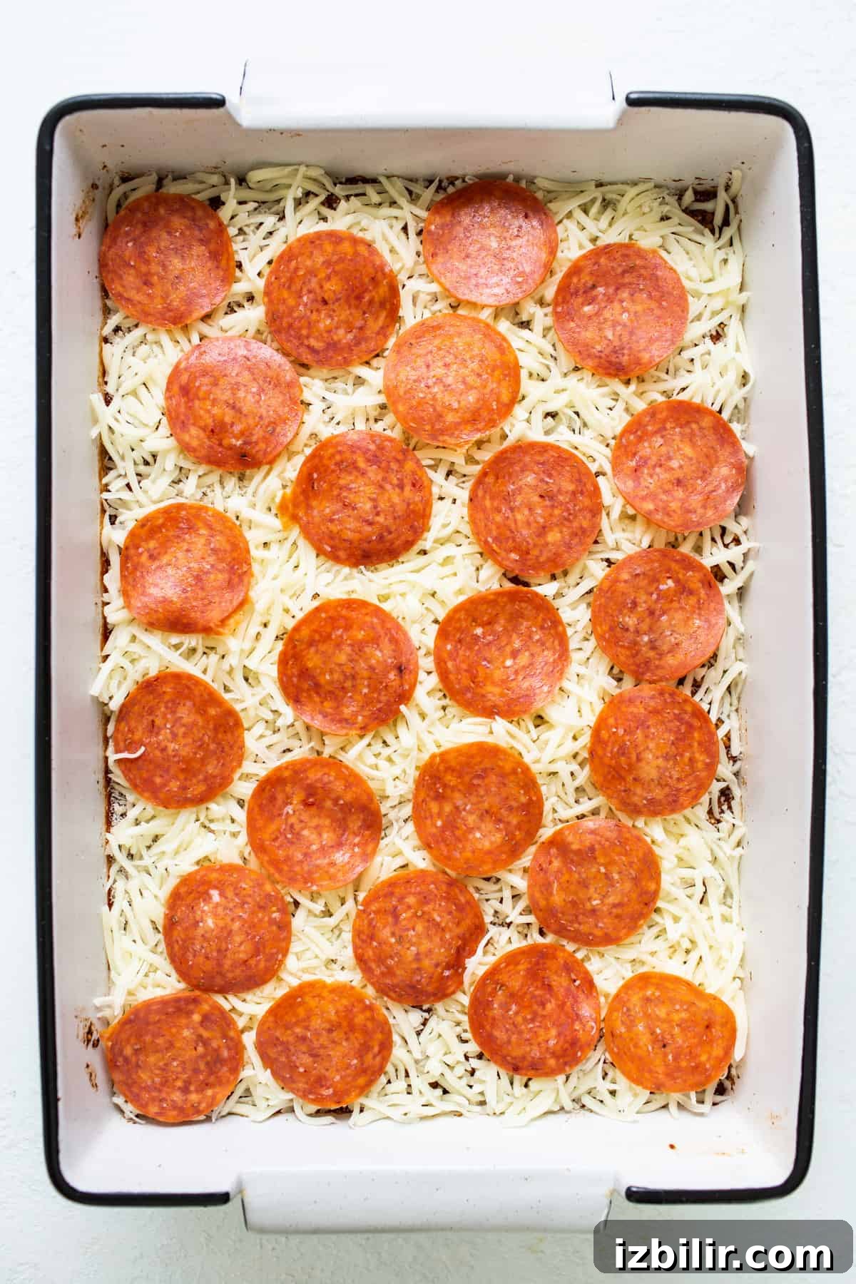 Pepperoni pizza in a baking dish with cheese on top.