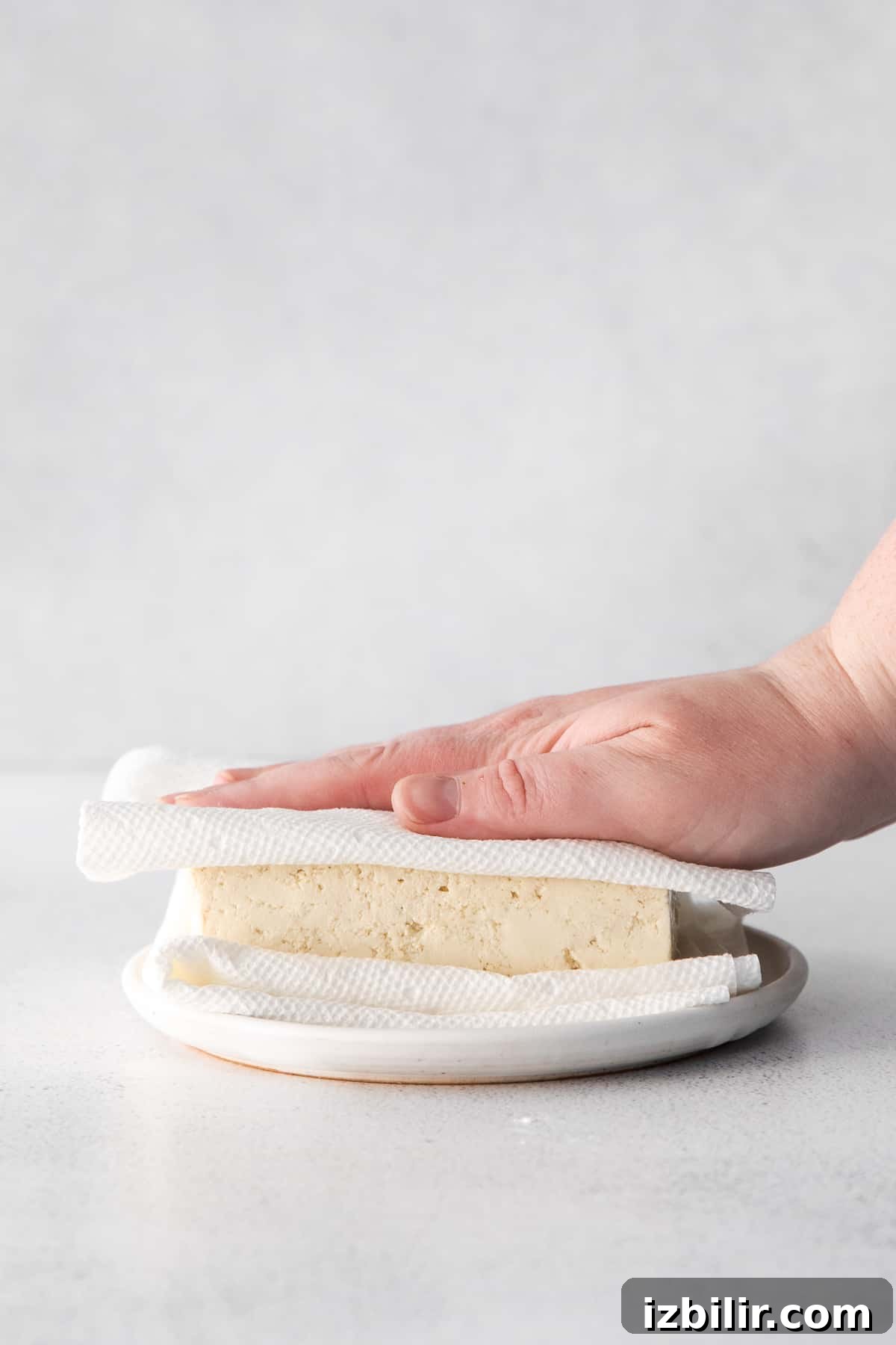 Removing moisture from tofu with a paper towel.