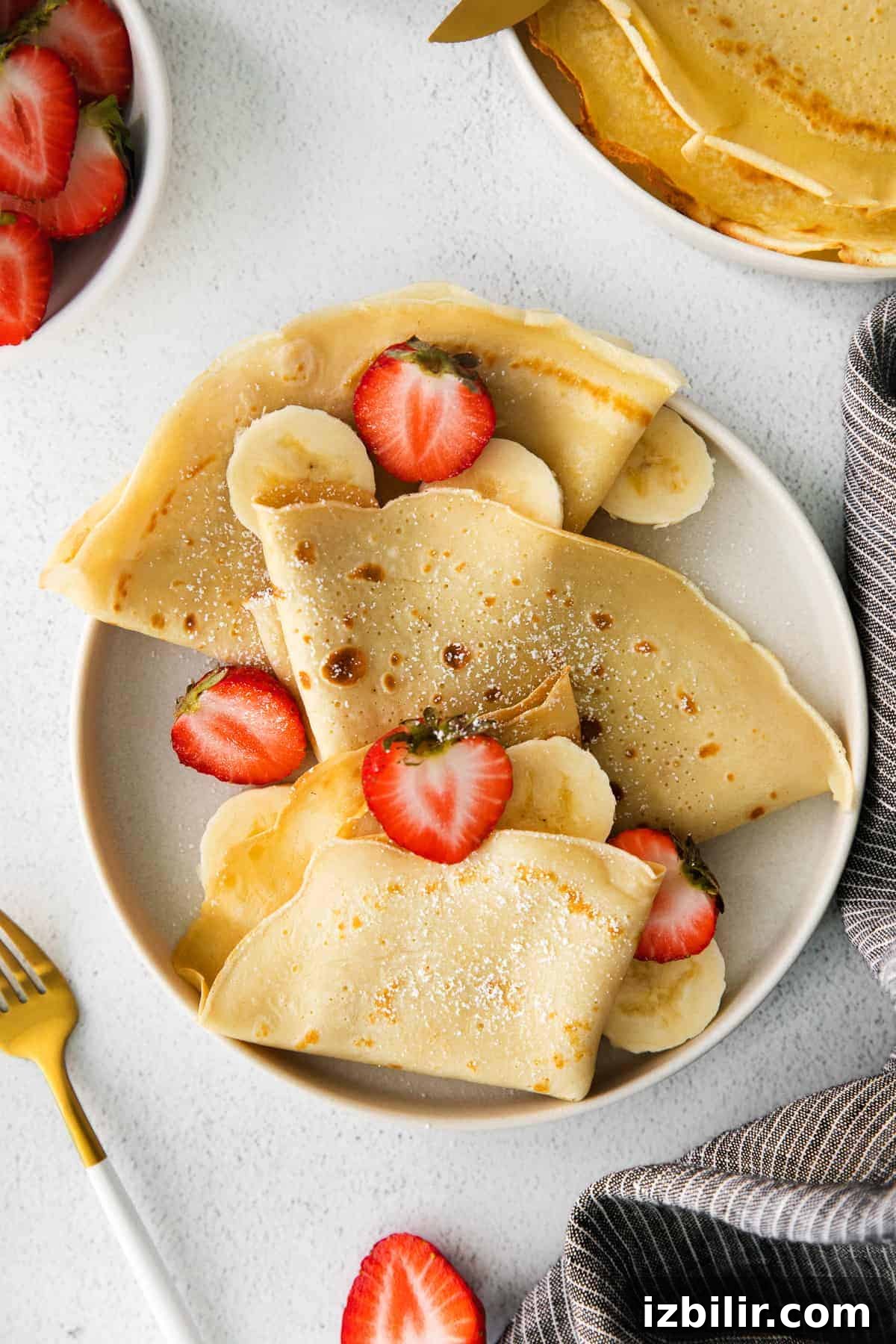 Crepes on a plate with strawberries and bananas.