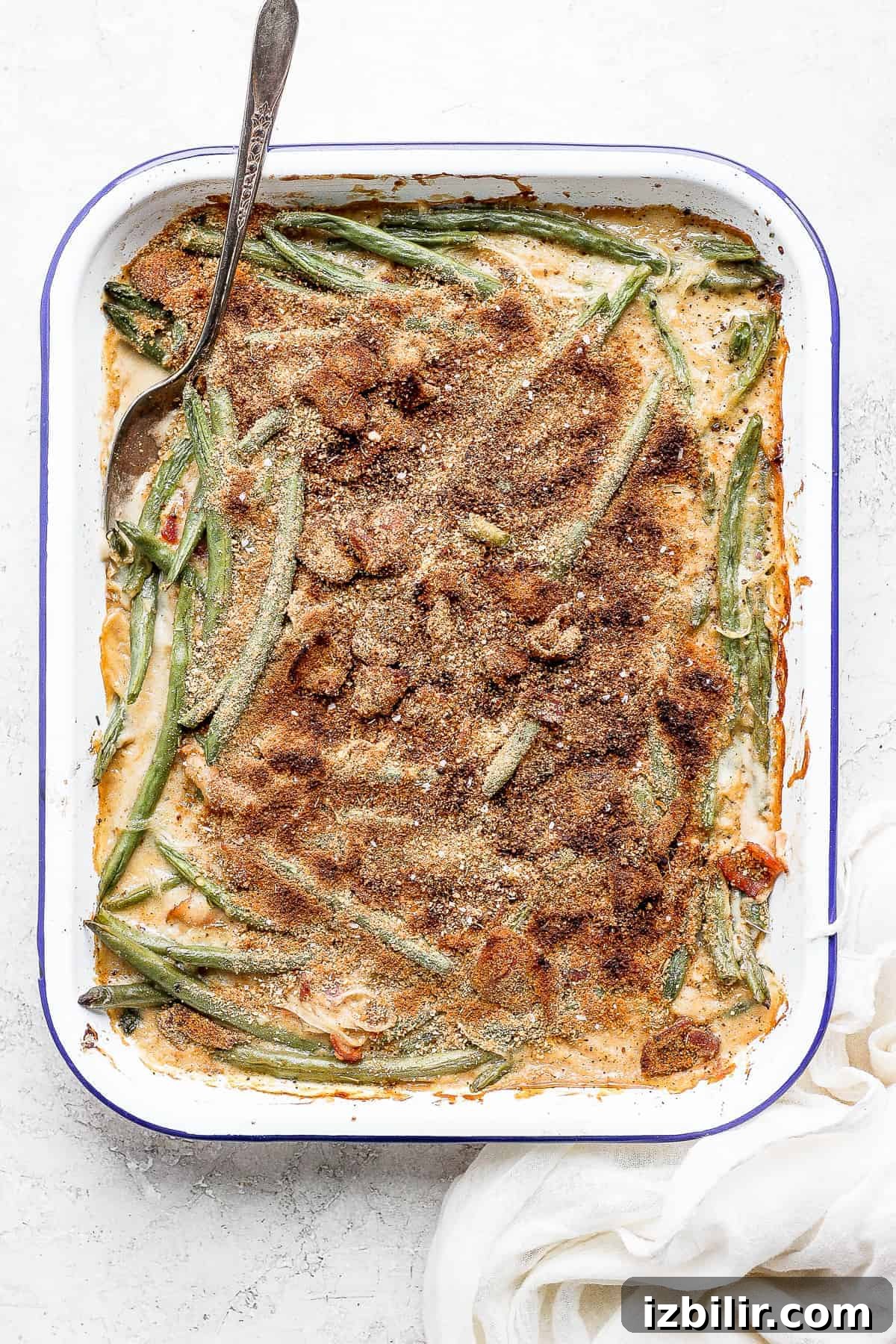 green bean casserole with bacon in a dish with a spoon