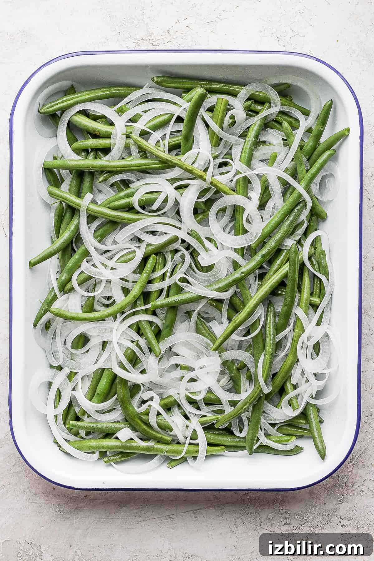 green beans and sliced onions in a casserole dish