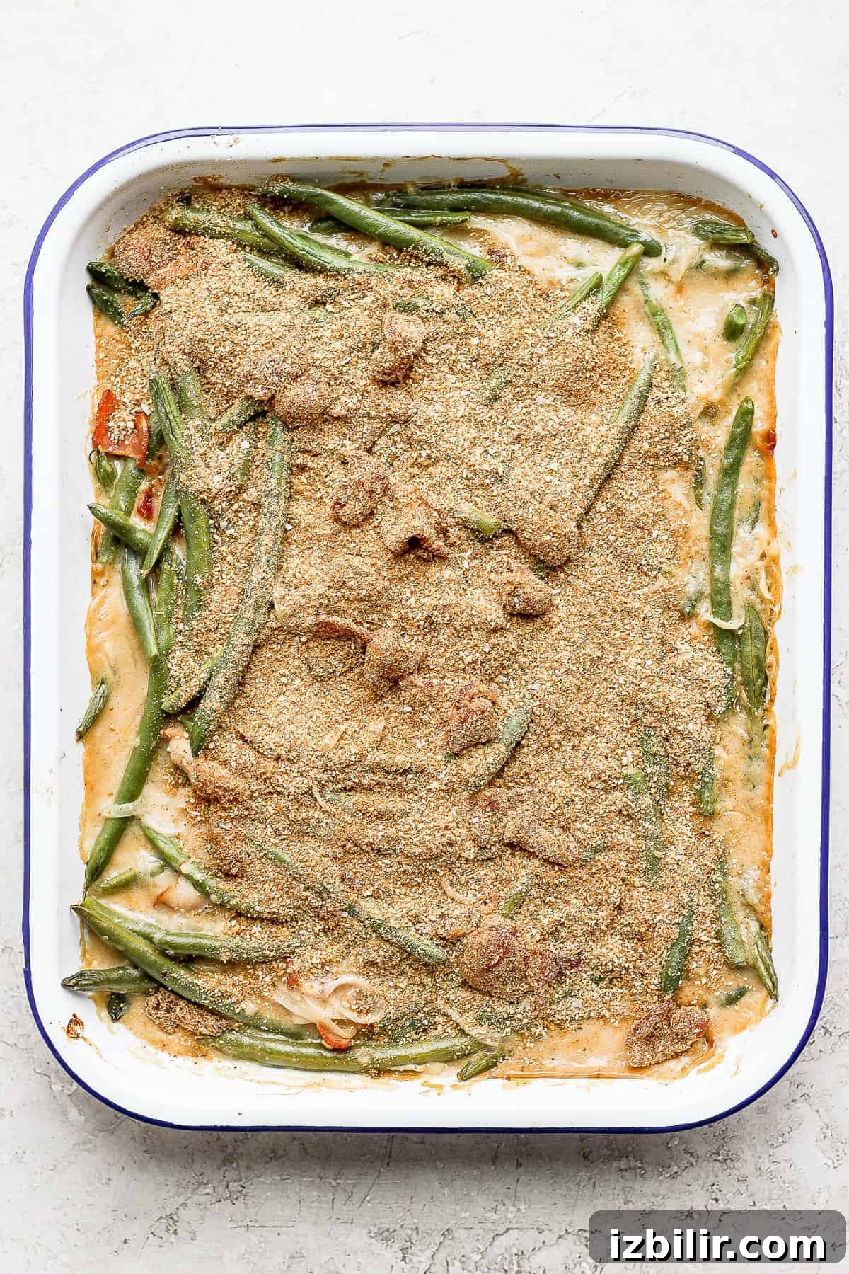 green bean casserole with bacon and a breadcrumb topping, ready to go in the oven
