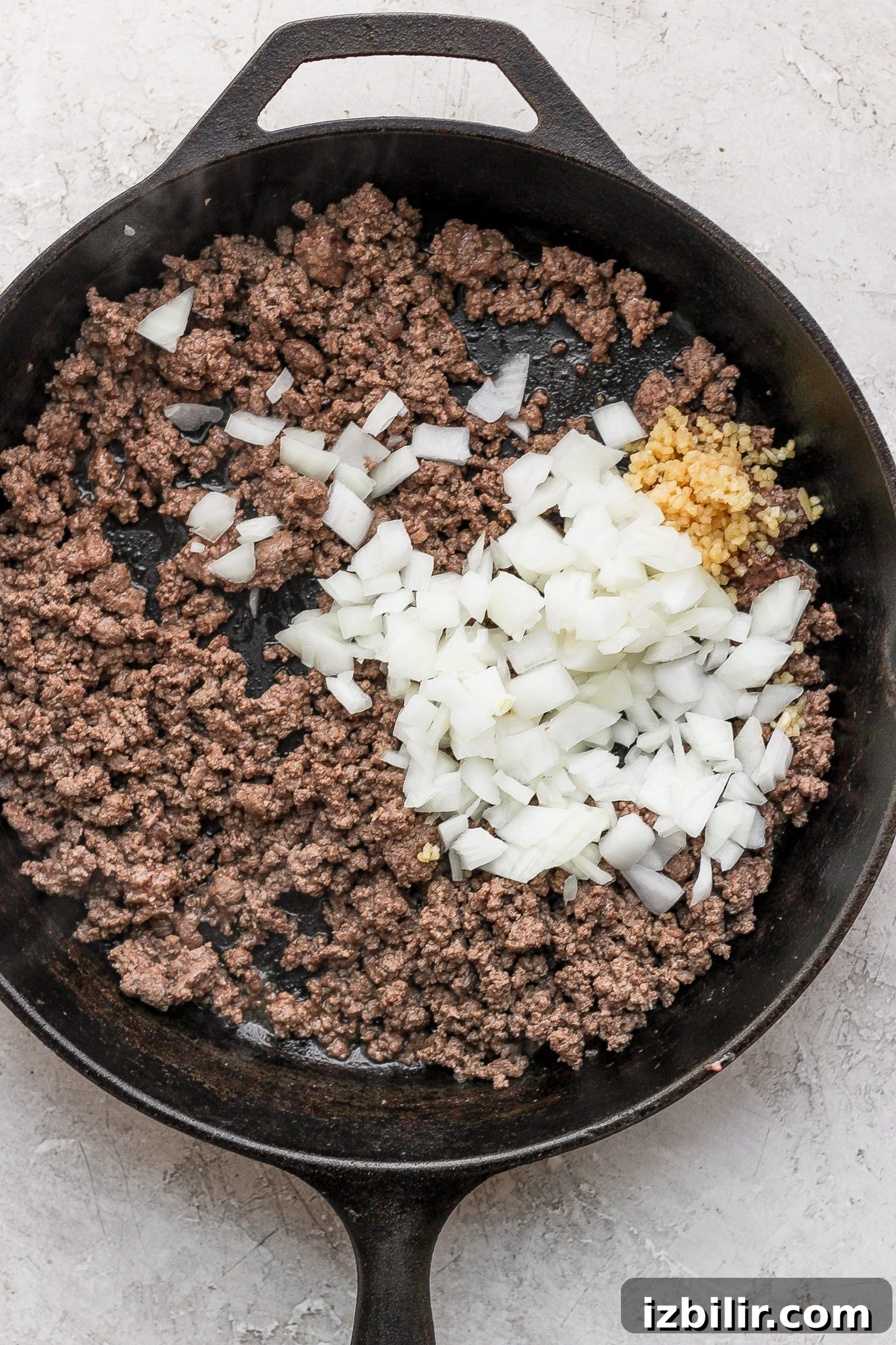 Browning ground beef and onions ground beef and diced onions in a cast iron skillet