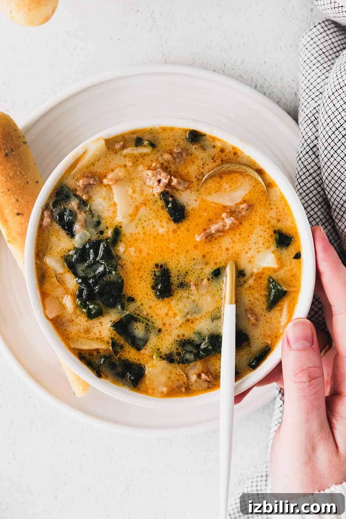 zuppa toscana soup in a bowl with a breadstick next to it