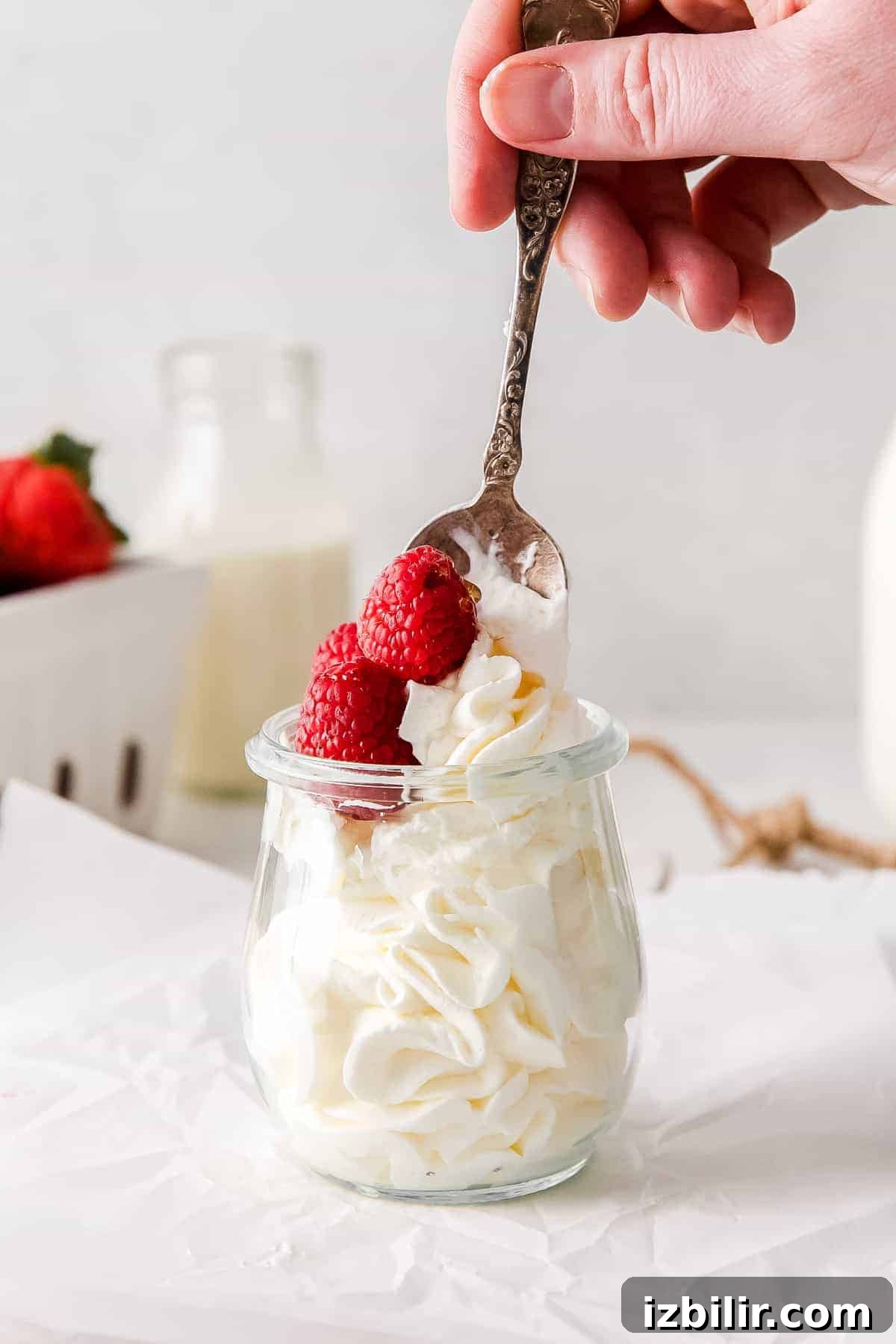 A spoon full of whipped cream and fresh raspberries.