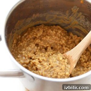 Oatmeal cooked in a pan with a wooden spoon.