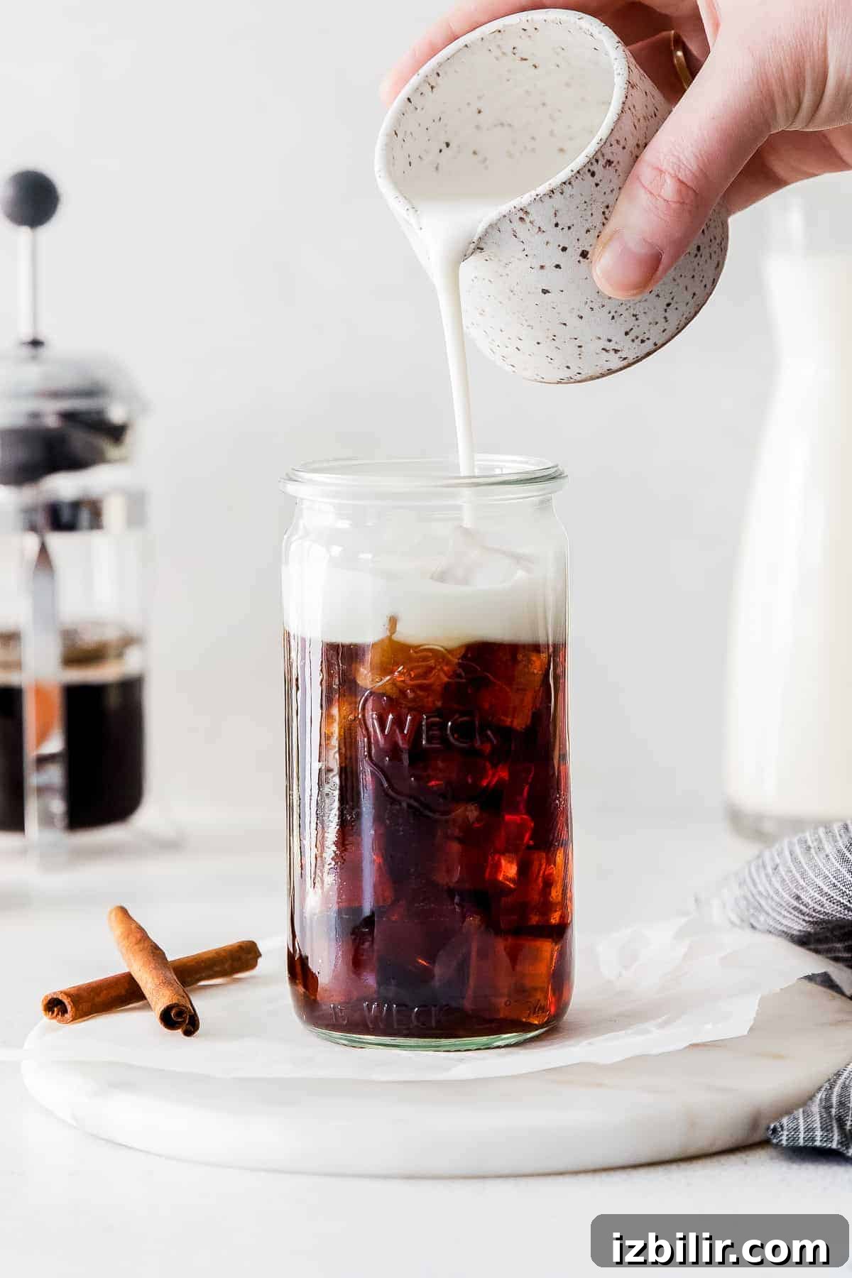 pouring oat milk in coffee glass