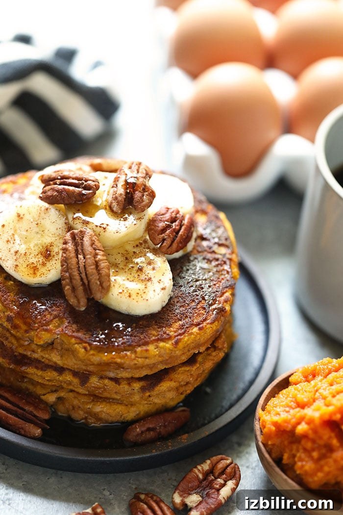 Paleo pumpkin pancakes topped with bananas and pecans. Paleo pumpkin pancakes on a plate topped with bananas and pecans.