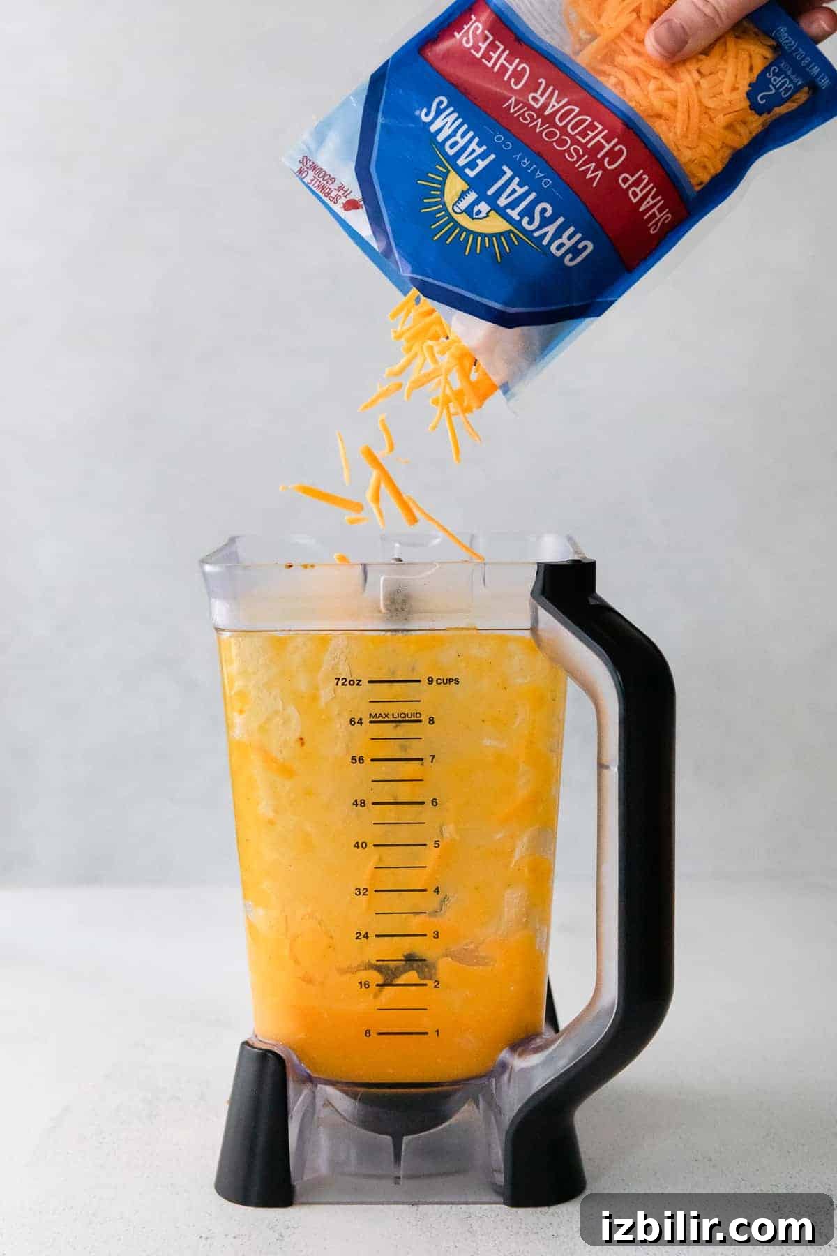 Shredded cheese being poured in a blender