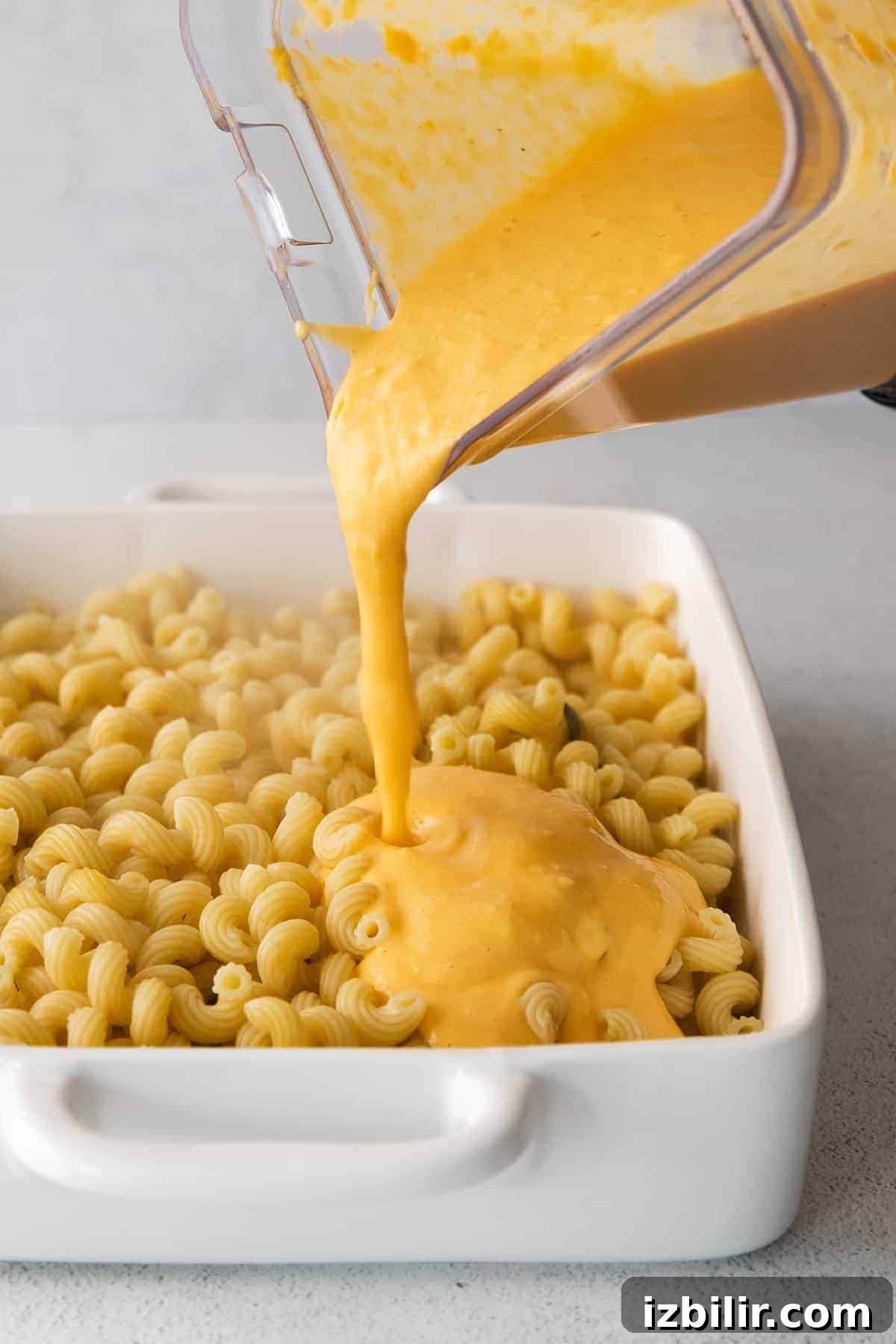 Butternut squash sauce being poured over cavatappi noodles