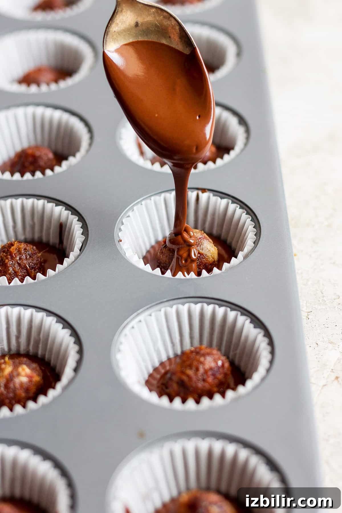 No-Bake Salted Caramel Date Cups Recipe 4 A spoon sprinkling chocolate over cupcakes in a muffin tin.