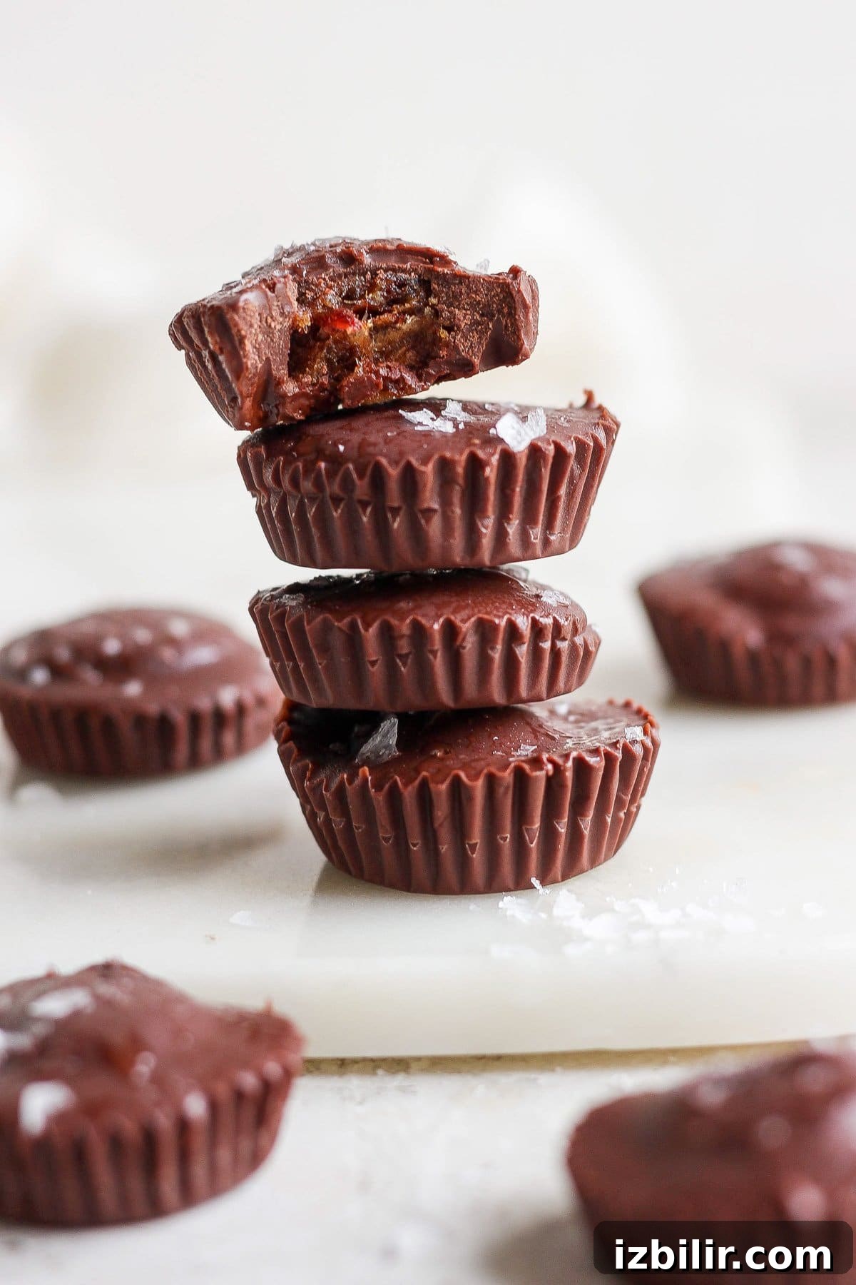 No-Bake Salted Caramel Date Cups Recipe 6 A stack of chocolate peanut butter cups on a cutting board.