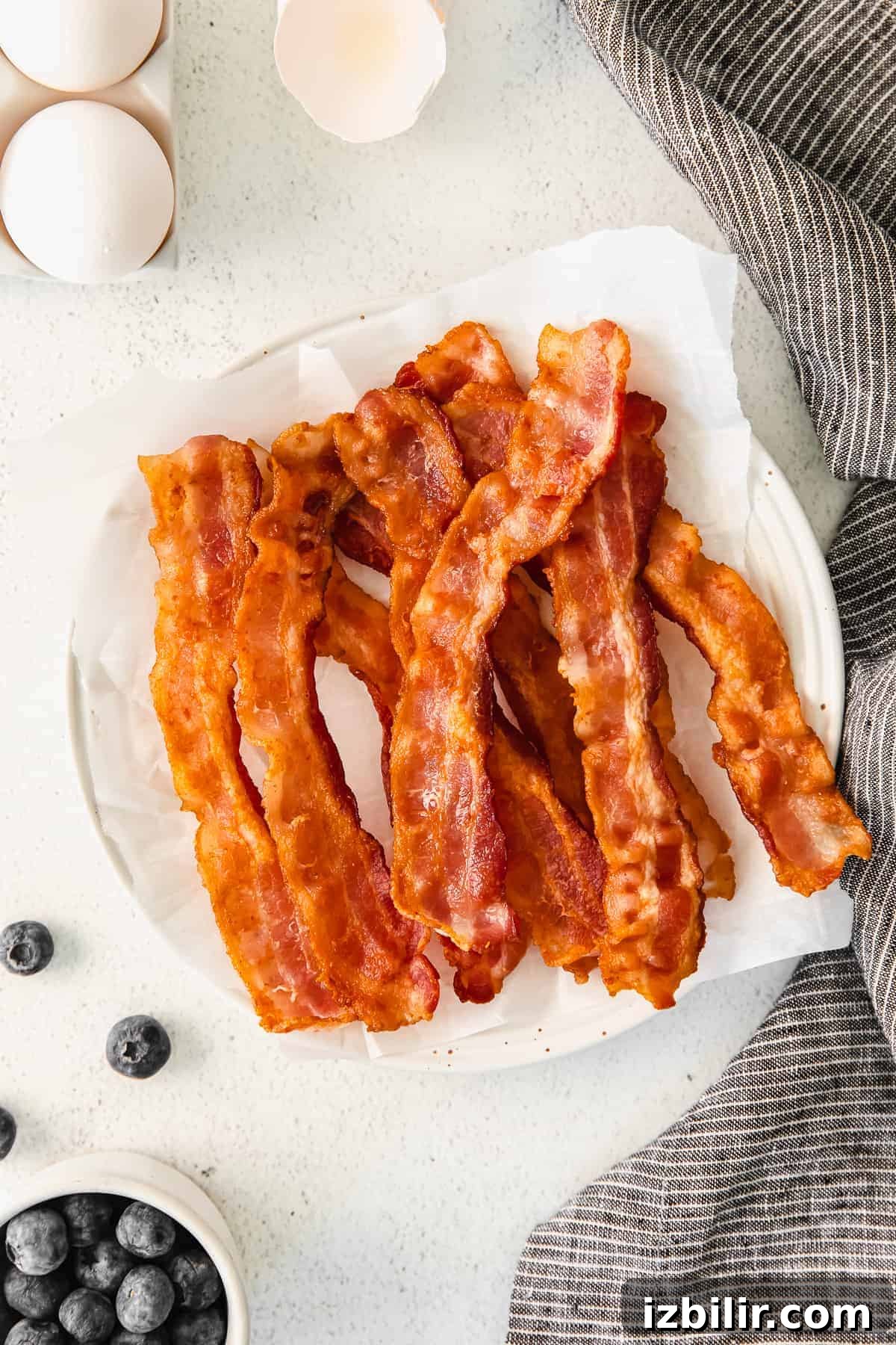 Learn how to cook bacon on the stove for a quick, no-fail way to make bacon! Your morning bacon will come out perfectly every time. bacon on plate