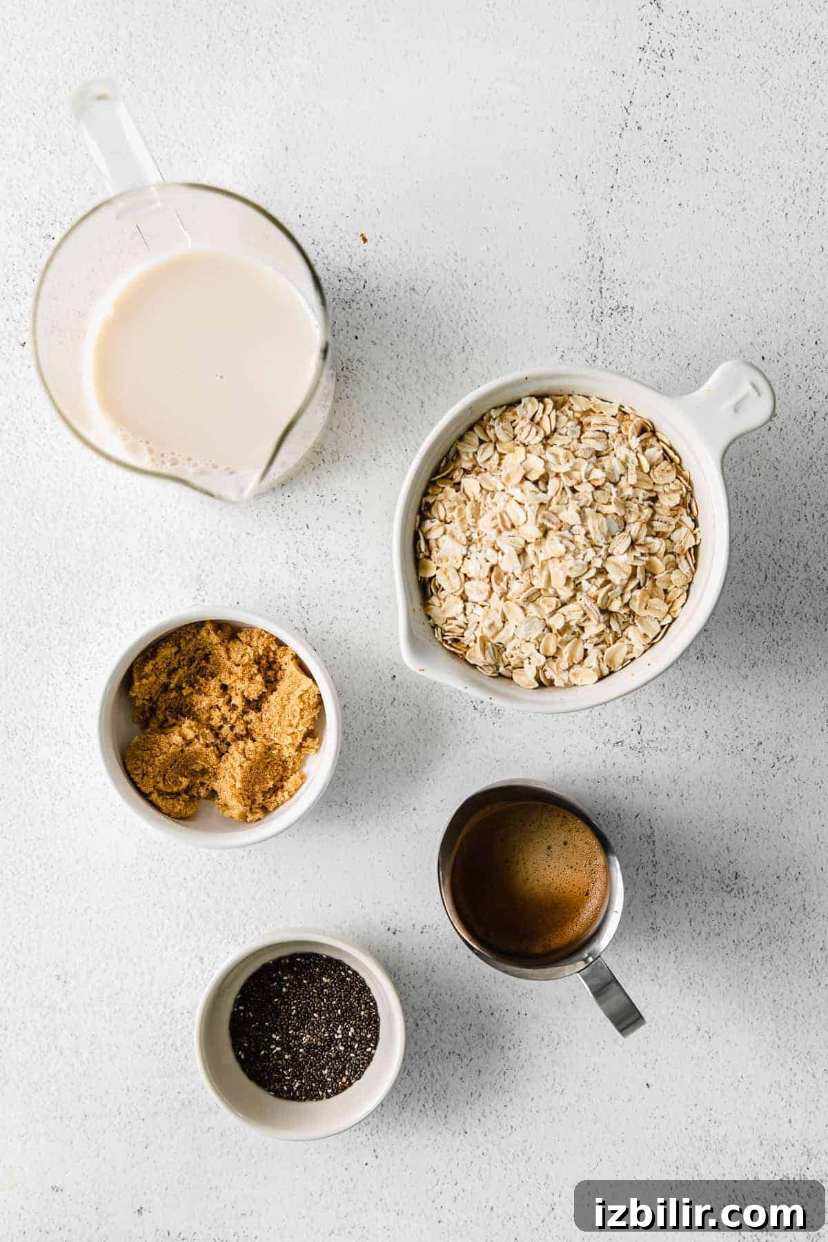 ingredients for brown sugar shaken espresso overnight oats laid out on a counter including rolled oats, brown sugar, chia seeds, almond milk, and espresso concentrate