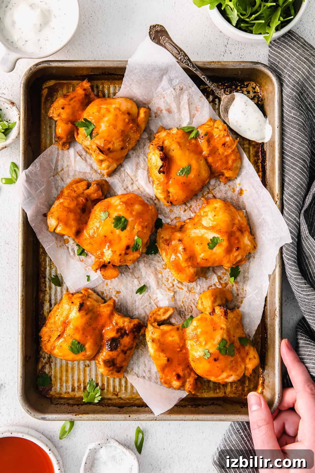 buffalo baked boneless chicken thighs on a baking sheet