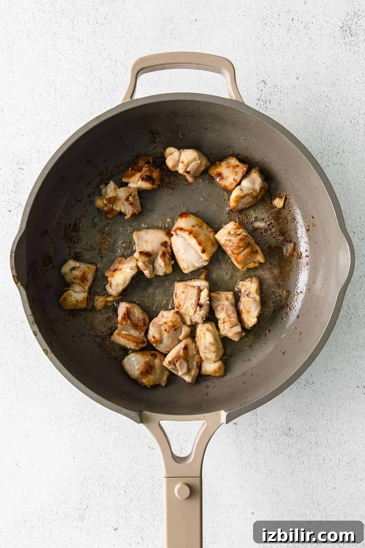 Chicken thighs browning in a skillet pan.